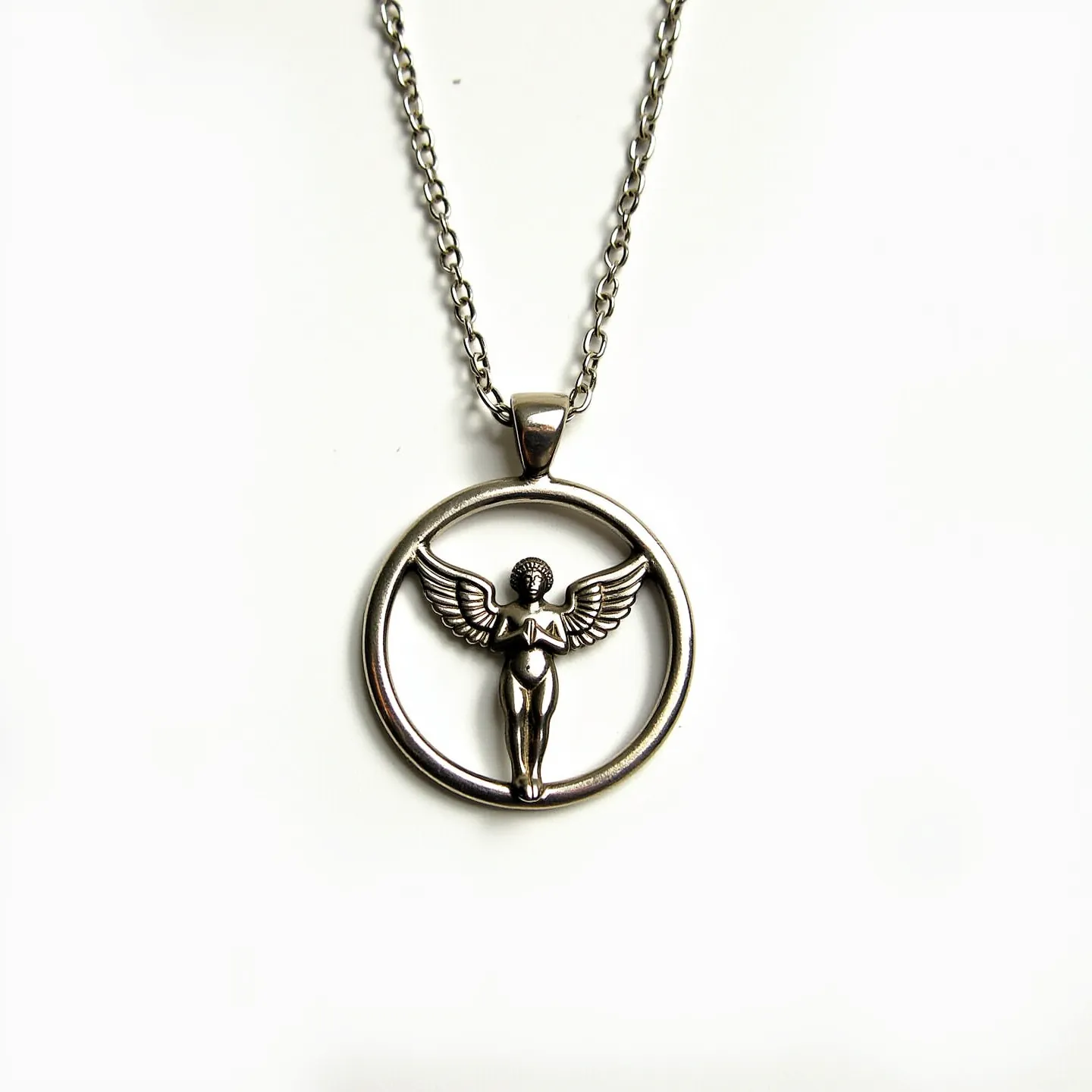 This angel necklace features a circular pendant with a detailed angel figure at its center, crafted from what appears to be a silver-toned metal. The angel is elegantly formed with outstretched wings, giving a sense of grace and movement. The pendant hangs from a medium-length, robust chain, which is composed of interlocking links that match the metal of the pendant, offering a cohesive look. The necklace is finished with a simple, functional clasp, allowing for easy wear and removal.