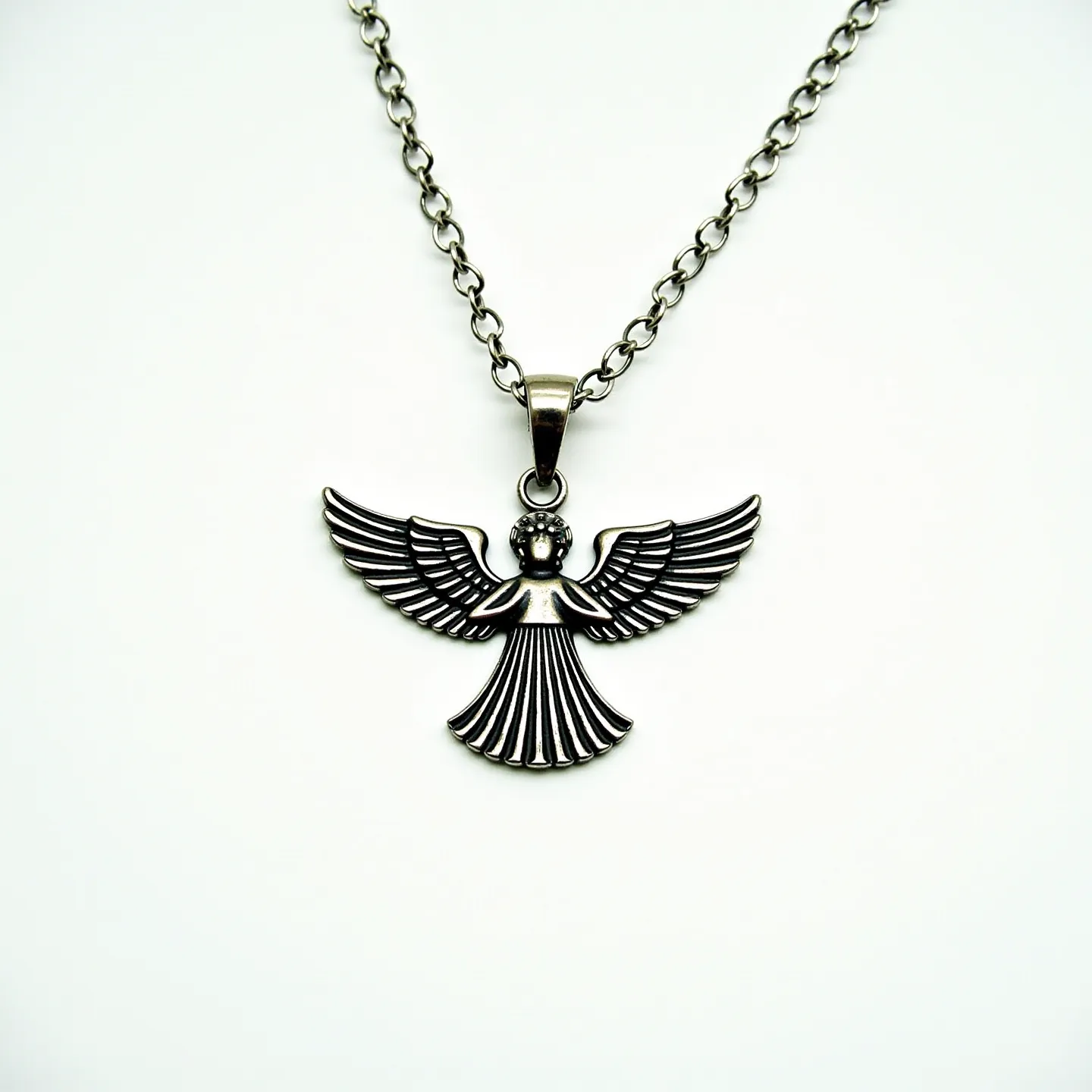 This angel necklace features a pendant crafted from a silvery metal depicting a stylized angel with detailed wings and a flowing gown. The angel's head and wings are intricately designed, adding texture and visual interest to the piece. The pendant is suspended from a chain with an interlocking loop design, typical of many durable necklaces. There is no visible use of gems, but the polished metal gives the necklace a radiant shine. It is attached via a loop bail that seamlessly connects the pendant to the chain, ensuring secure wearability.