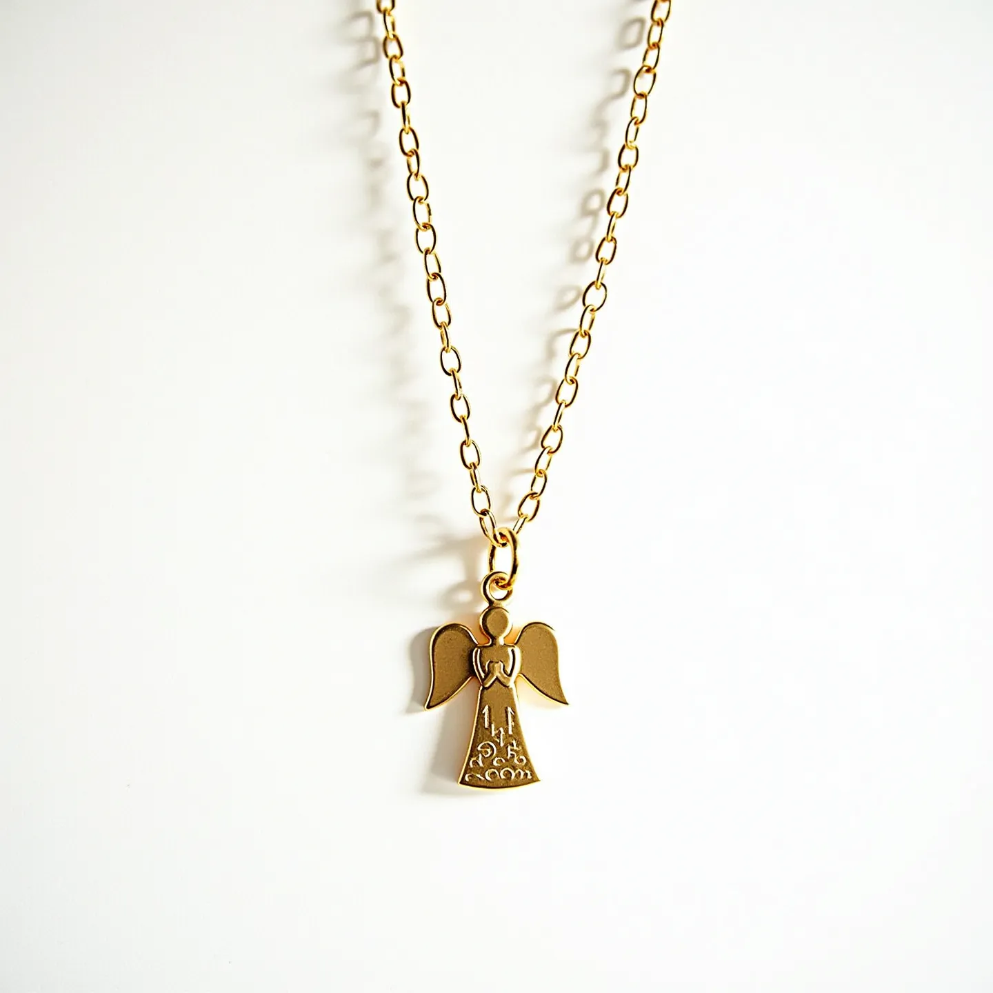 This angel necklace features a delicately crafted angel charm made of metal, likely gold or gold-toned, displaying elegant detailing on its wings and dress. The pendant hangs from a simple yet elegant chain comprising oval links, which matches the hue of the pendant. The chain's construction suggests a secure, straightforward clasp for fastening around the neck. The charm is connected to the chain by a small loop, providing fluid movement and allowing the angel to hang gracefully as part of the necklace's design.