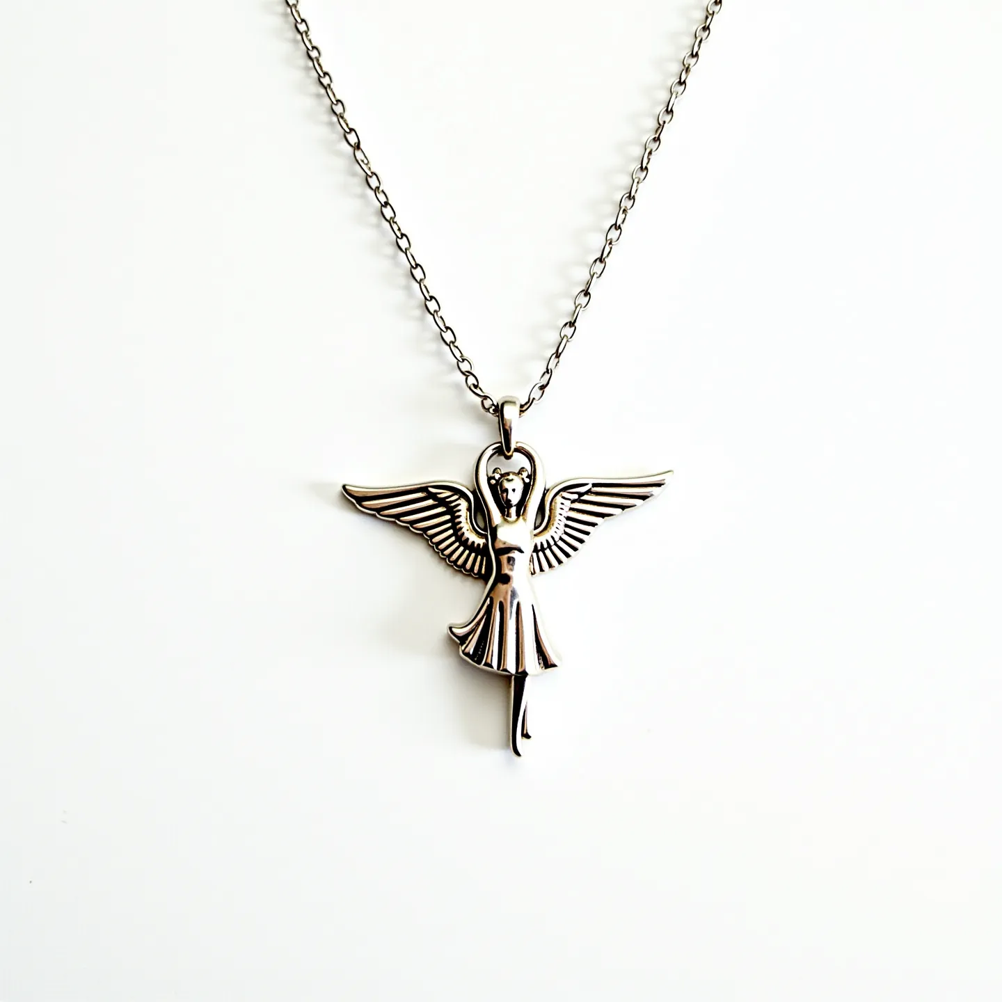 This angel necklace features a delicate chain supporting a sculpted angel pendant. The pendant appears to be crafted from a metal with a silver-like finish, which may be indicative of sterling silver or a similar alloy. The angel design is intricate, showcasing detailed wings and a flowing gown. There are no visible gems or stones embedded within the piece, focusing instead on the detailed metalwork. The chain appears to have a simple link design, suggesting a classic, understated style, and is likely fastened with a standard clasp, providing secure attachment.