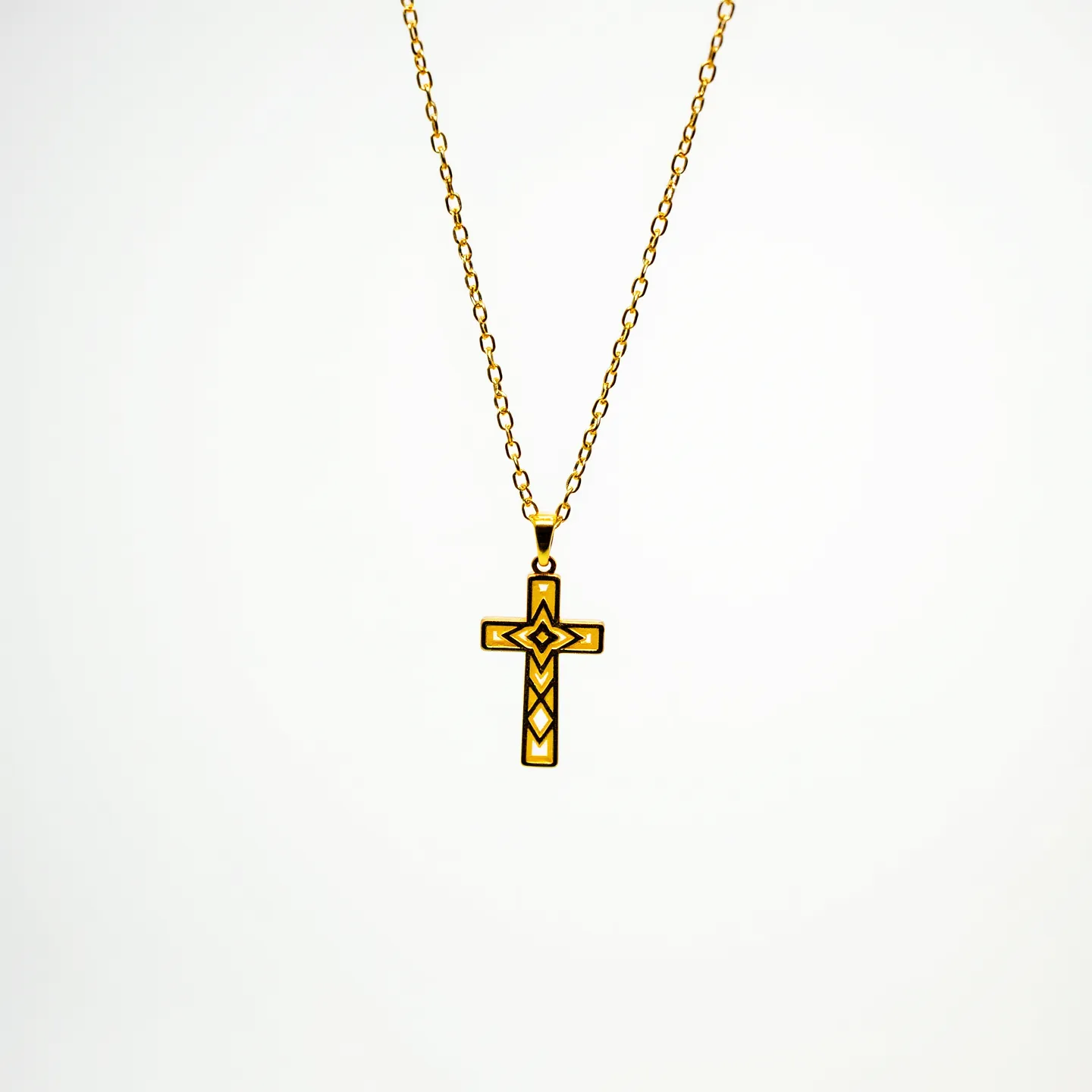 This baby cross necklace features a delicate gold-toned chain supporting a minimalistic cross pendant. The cross is adorned with geometric patterns, creating an intriguing design. The pendant appears to be made of a similar gold-toned material, and there is no visible stone or gem setting. The necklace is secured with a simple loop attachment connecting the cross to the chain, providing a streamlined and elegant look suitable for a baby.