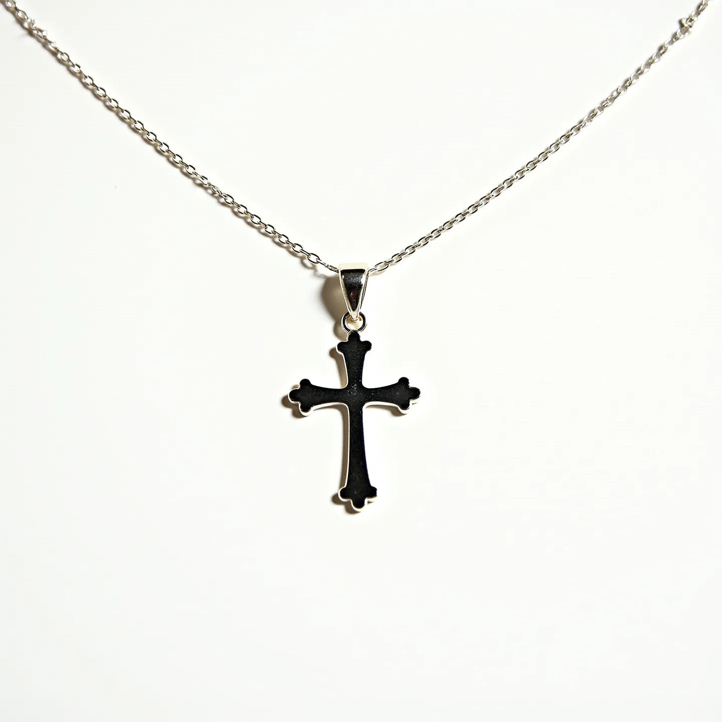 This baby cross necklace features a sleek, simple design with a small cross pendant crafted from a shiny metal, possibly sterling silver, as indicated by its reflective appearance. The cross has curved tips at each arm, adding a touch of elegance to the minimalist style. It is attached to the chain via a small metal bail that secures the pendant. The chain is dainty, with fine links that enhance the delicate nature of the necklace. The clasp is a subtle, standard type, likely a spring ring or lobster clasp, ensuring a secure closure. This necklace is designed to be a charming and understated piece suitable for everyday wear.