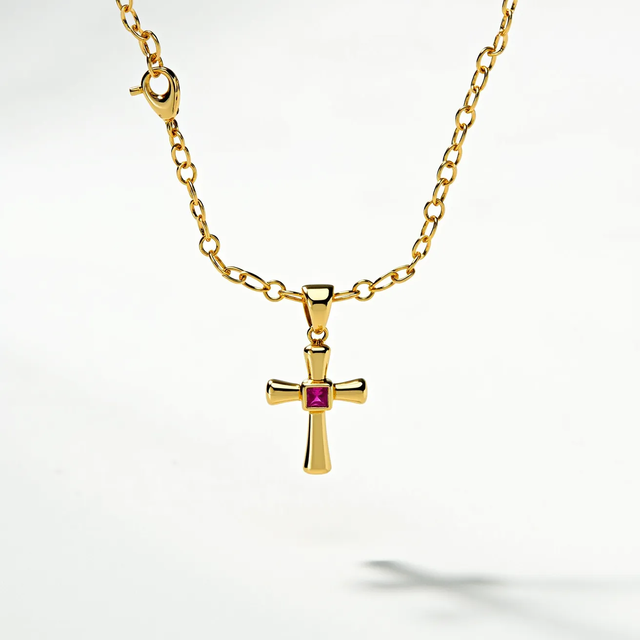 This baby cross necklace features a delicate gold chain with links evenly spaced in a classic design. At the center hangs a polished gold cross pendant that showcases a small, square-cut red gemstone set securely in a bezel at the intersection. The vibrant stone adds a touch of color and elegance to the overall piece. The necklace is fastened with a gold spring ring clasp, ensuring secure wear while maintaining the piece’s refined appearance.