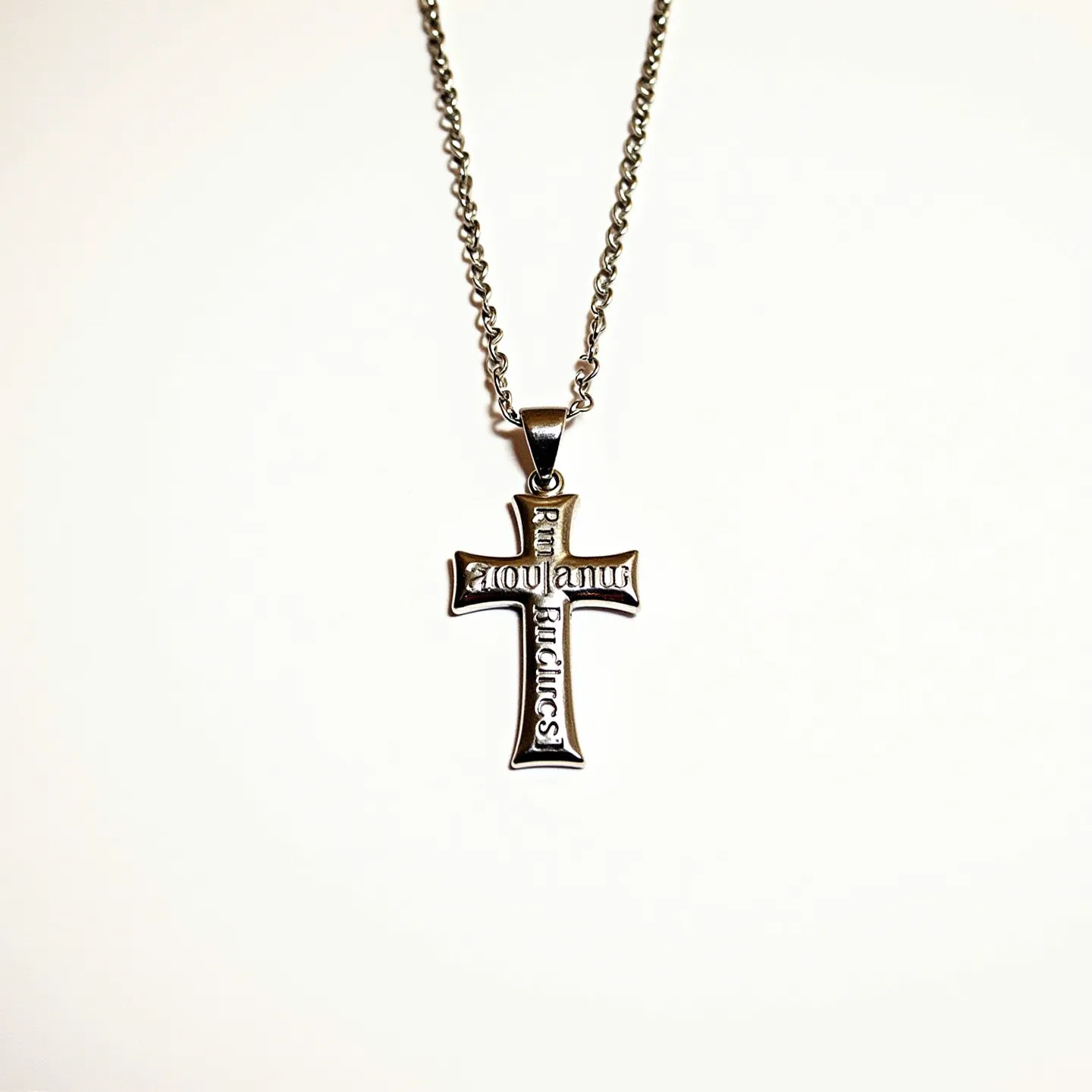 This baby cross necklace features a sleek, metallic design crafted from what appears to be stainless steel or a silver-toned metal. The pendant has engraved lettering across its surface, adding a personalized and detailed touch to the piece. It hangs from a matching chain that showcases a simple yet secure lobster clasp, ensuring ease of wearing and removal. The necklace is devoid of any gemstones or additional ornamentation, focusing instead on the polished finish and engraved elements for its aesthetic appeal.