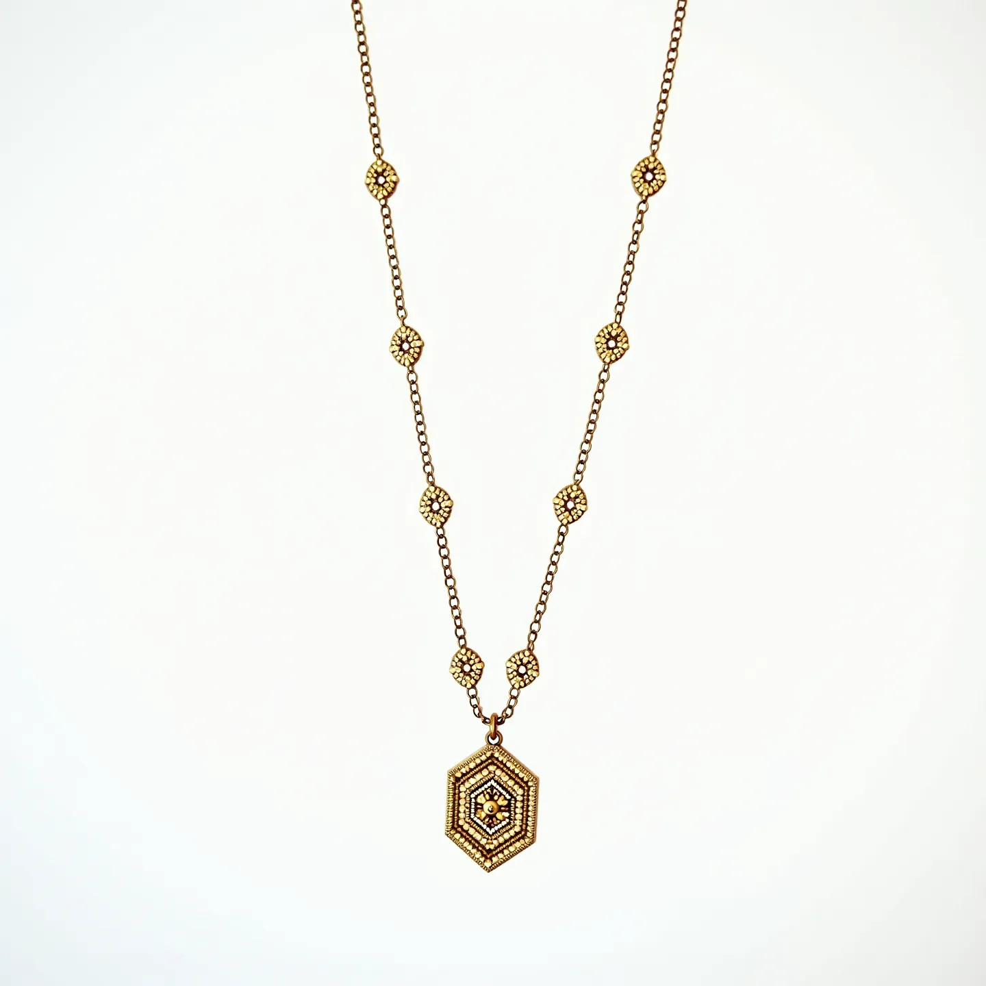 This beaded necklace features a series of intricately designed hexagonal beads, each adorned with small, round, metallic elements that create a textured surface. The chain itself is an elegant metal of a warm, golden hue, complementing the beadwork. At the center of the necklace hangs a prominent hexagonal pendant, similarly embellished and reflecting a harmonious pattern that echoes the smaller beads. The necklace likely uses a classic clasp mechanism to secure it. The overall design presents a vintage aesthetic, highlighted by the recurring geometric forms and detailed beadwork.