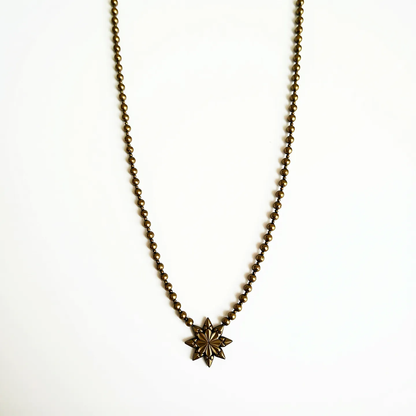 This beaded necklace features a series of small, uniformly sized metallic beads that create a sleek and cohesive design. At the center, a prominent star-shaped pendant adds a striking focal point. The star appears to be crafted from the same metallic material as the beads and exhibits a polished finish, enhancing the overall elegance of the piece. The necklace is likely completed with a discreet clasp that provides a secure and functional closure, ensuring ease of wear while maintaining the aesthetic integrity.