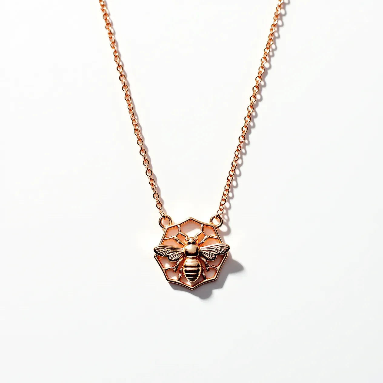 This bee necklace features a delicate pendant design crafted in a warm rose gold metal tone. Central to the piece is an intricately detailed bee motif, set against a honeycomb-shaped backdrop, which further emphasizes the bee theme. The chain is a simple, elegant link style, complementing the pendant's design. The necklace likely uses a standard lobster clasp for secure fastening. The attention to detail in the bee's wings and body adds to the necklace's charm and appeal, making it a stylish accessory.