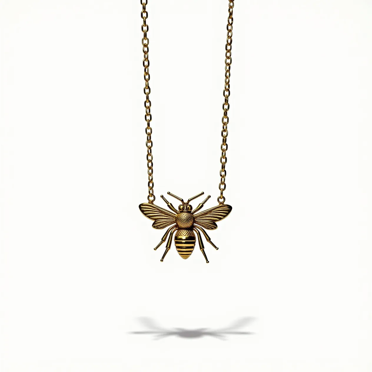 This bee necklace features a detailed bee pendant crafted from a gold-toned metal, showcasing intricate texturing on the wings and body. The pendant is attached to a matching gold-toned chain, which complements its aesthetic. The bee design does not include any gems or stones, focusing instead on the metallic craftsmanship. The chain is composed of elongated links, suggesting durability and elegance. A standard clasp mechanism is present for secure fastening, ensuring that the necklace can be worn comfortably.