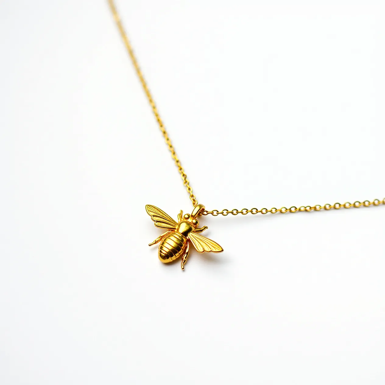 This bee necklace features a delicate chain crafted from a lustrous gold-colored metal, likely gold or gold-plated for a warm, elegant appearance. The pendant is a beautifully detailed bee motif, showcasing a polished finish that highlights the intricate design of the wings and body. There are no visible gemstones incorporated into the design, enhancing the metal's natural shine. The chain appears to have a standard lobster clasp, providing a secure closure for easy wear. The overall look of the necklace is both charming and sophisticated, suitable for various fashion styles.