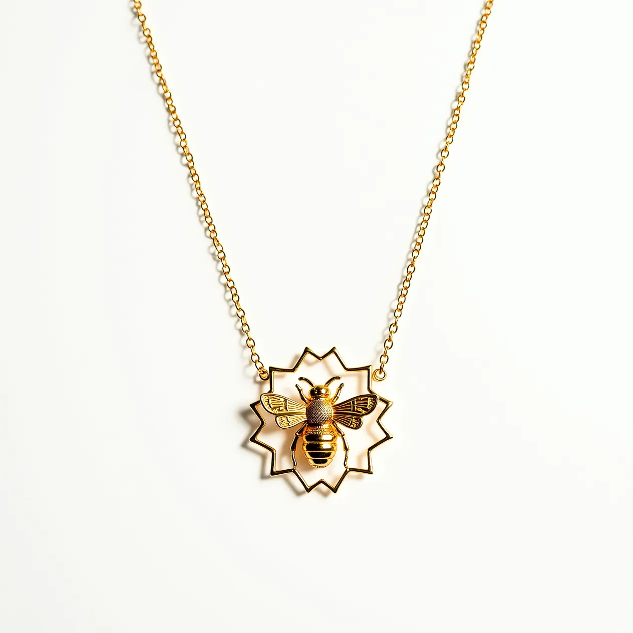 This bee necklace features a striking design with a central bee motif crafted in a gold-tone metal. The bee is intricately detailed, with textured wings and body, and is set within a starburst frame that adds a touch of geometric elegance. The necklace is attached to a delicate gold-tone chain, which complements the bee motif and enhances the overall aesthetic. The clasp appears to be a standard spring ring, providing a secure and convenient closure. This accessory combines whimsical natural imagery with a modern design, making it a versatile piece for various styles.