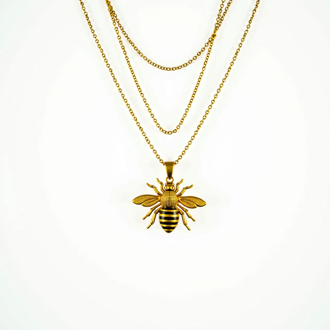 This bee necklace features a striking pendant crafted from a gold-toned metal, intricately designed to resemble a bee with detailed wings and a segmented body. The pendant hangs from multiple fine chains, also gold-toned, giving the piece an elegant, layered look. The bee's body, possibly adorned with black enamel stripes, adds contrast and dimension to the design. The necklace is complete with a standard clasp, ensuring secure attachment when worn. The craftsmanship highlights the bee's anatomy with precision, making it both a fashionable and symbolic accessory.