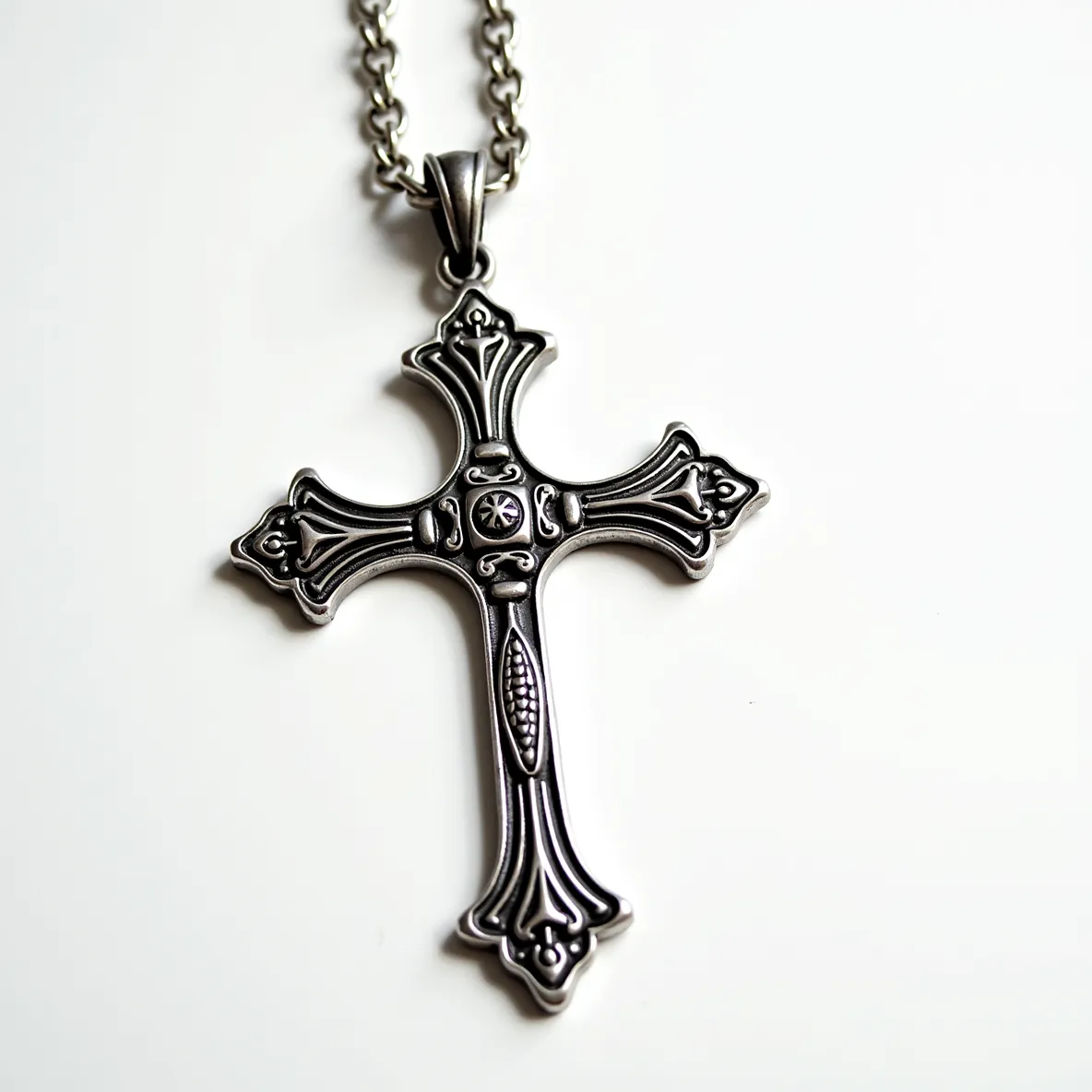 This big cross necklace is crafted from a metallic material, likely stainless steel or silver, exhibiting a polished and intricate design with a Gothic style. The cross features ornate, raised embellishments along its arms, showcasing a central round gem-like accent. The gemstone, if present, is subtle and integrated into the cross's central motif, potentially a small round diamond or crystal set into the center in a bezel setting. The chain attached to the cross is robust, with a series of interlinked round or oval metal loops, providing durability and a seamless connection to the pendant via a secure bail or loop.