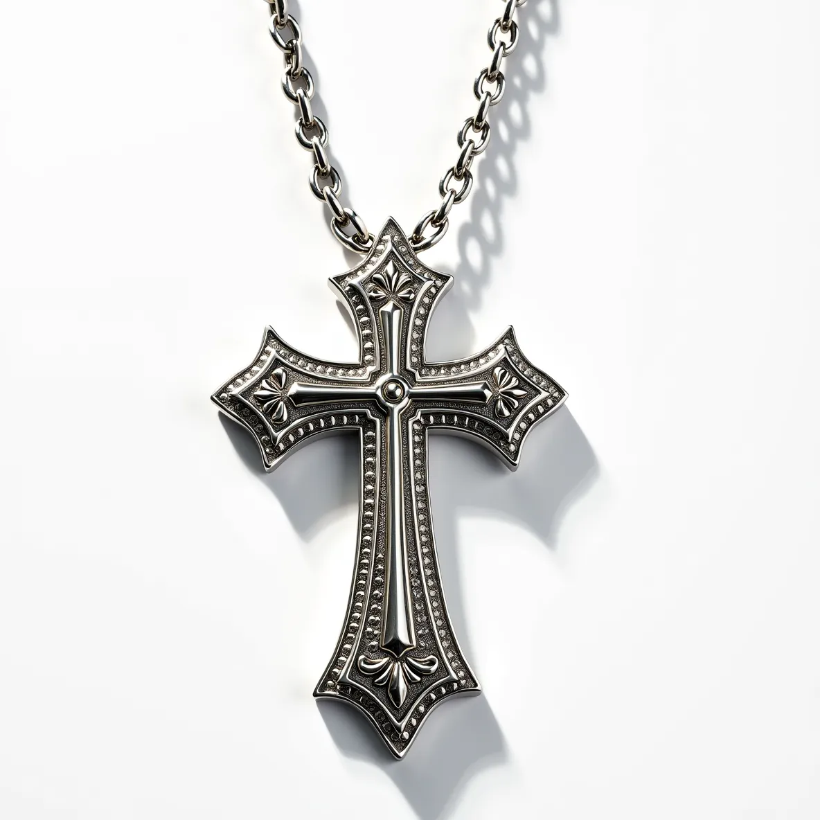 This big cross necklace features an intricately designed silver cross with a polished finish, showcasing ornate detailing along its edges. The cross is adorned with a single, centrally placed round gem, which is set in a bezel style. The overall design includes floral motifs that add to its decorative appeal. The chain attached to the cross is composed of robust metal links, providing both durability and a complementary aesthetic to the pendant. The necklace is secured with a classic lobster clasp, ensuring ease of wear and reliability.