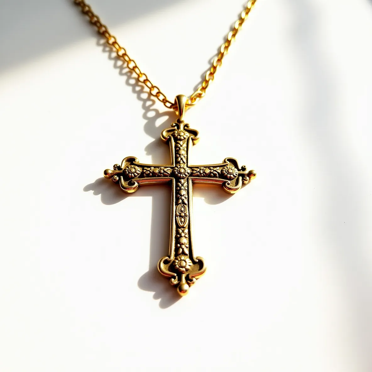 This big cross necklace features an intricate design with ornate detailing on a gold-toned metal. The cross has decorative floral and vine motifs embossed along its surface, suggesting a vintage or baroque style. At the center and terminals of the cross, the embellishments add depth and texture, enhancing the piece's elegance. The chain is a matching gold tone with a simple, classic link style, allowing the cross to remain the focal point. The pendant is attached to the chain by a small, unobtrusive bail, ensuring a seamless connection that enables smooth movement when worn.