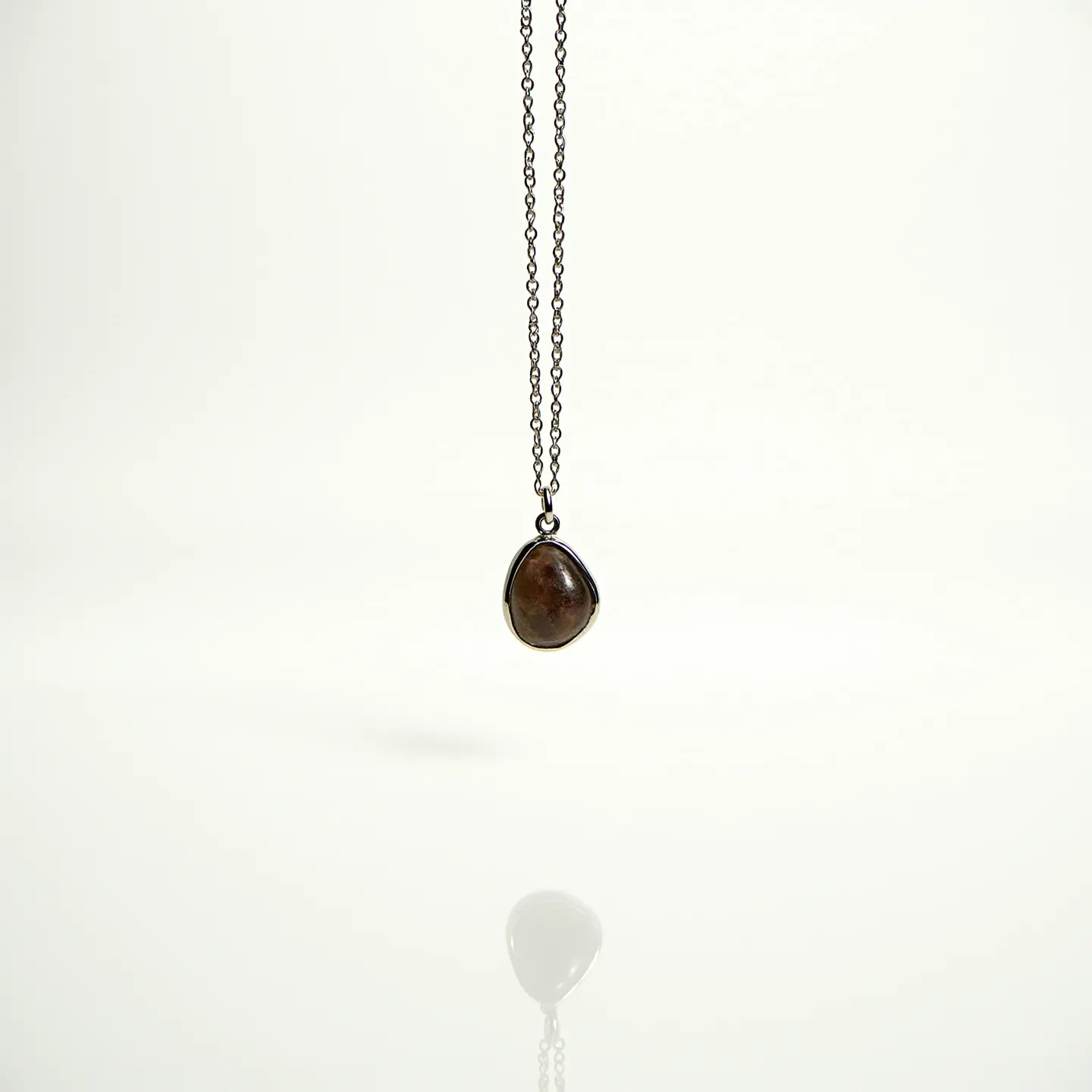 This birthstone necklace features a polished, teardrop-shaped stone encased in a smooth, dark bezel setting, possibly made of oxidized silver for a vintage look. The chain is comprised of delicate links, suggesting a lightweight and elegant design. The stone's earthy hues add a natural appeal, subtly reflecting light. The necklace is completed with a typical clasp mechanism, ensuring secure wear. Overall, the necklace combines simplicity with understated elegance, making it a versatile accessory.