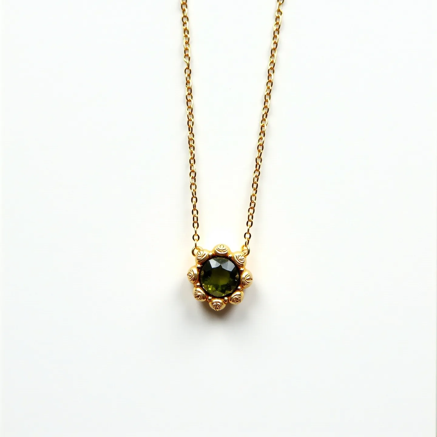 This birthstone necklace features a delicate gold chain that supports a prominent green gemstone as its focal point. The stone is likely peridot, which is the birthstone for August, and is cut into a round shape, showcasing its vibrant hue. It is set in a unique bezel or claw setting with intricate gold detailing resembling a floral motif that adds an elegant touch. The stone's setting complements the overall aesthetic, and the necklace is finished with a discrete clasp that ensures a secure and comfortable fit.