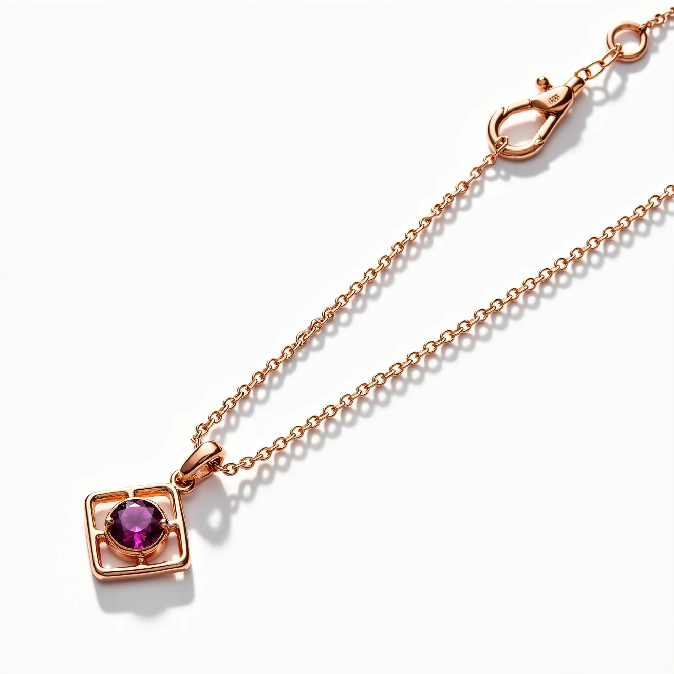 This birthstone necklace features a delicate rose gold chain linking to a striking pendant. The pendant showcases a round amethyst stone, set within a geometric square framework that highlights its vibrant purple hue. The cut of the gemstone radiates brilliance, enhancing its visual appeal. The lobster clasp ensures secure fastening and easy wearing, complementing the necklace's elegant design with practicality. The combination of the rosy metal and the richly colored gemstone presents a harmonious and sophisticated piece.