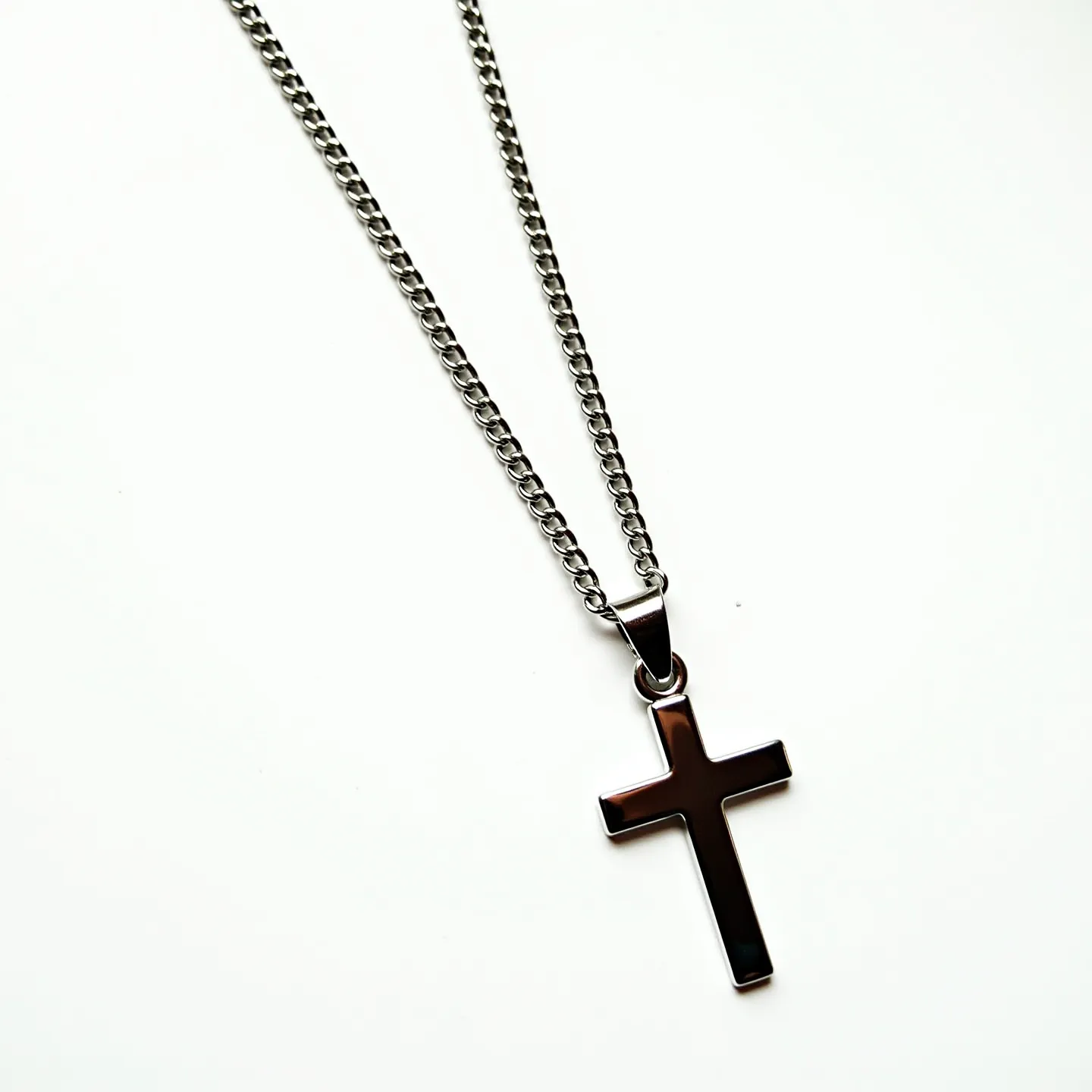 This boys chain necklace features a sleek, metallic design, likely crafted from stainless steel or a similar metal for durability and a polished appearance. The chain itself is composed of interlocking links, providing both sturdiness and flexibility. Attached is a cross pendant with a smooth, reflective surface, emphasizing modern simplicity without the inclusion of any gems or stones. The pendant is suspended from the chain by a sturdy bail, ensuring secure attachment. Although the clasp is not visible in this view, the overall design suggests a practical and enduring accessory suitable for everyday wear.