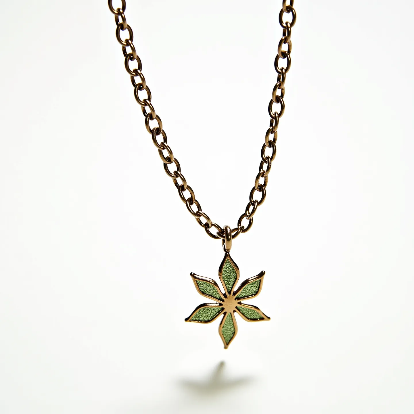 This boys chain necklace features a bronze or gold-toned metal chain, consisting of oval links that are interconnected to form a classic chain style. The pendant is designed in the shape of a stylized flower, with six petals containing green enamel inlays that add a pop of color and texture. The pendant is attached to the chain via a simple loop, allowing it to dangle freely. There are no visible gemstones or additional adornments within the pendant or chain structure. The necklace likely uses a standard clasp or attachment, though it is not visible in this view.