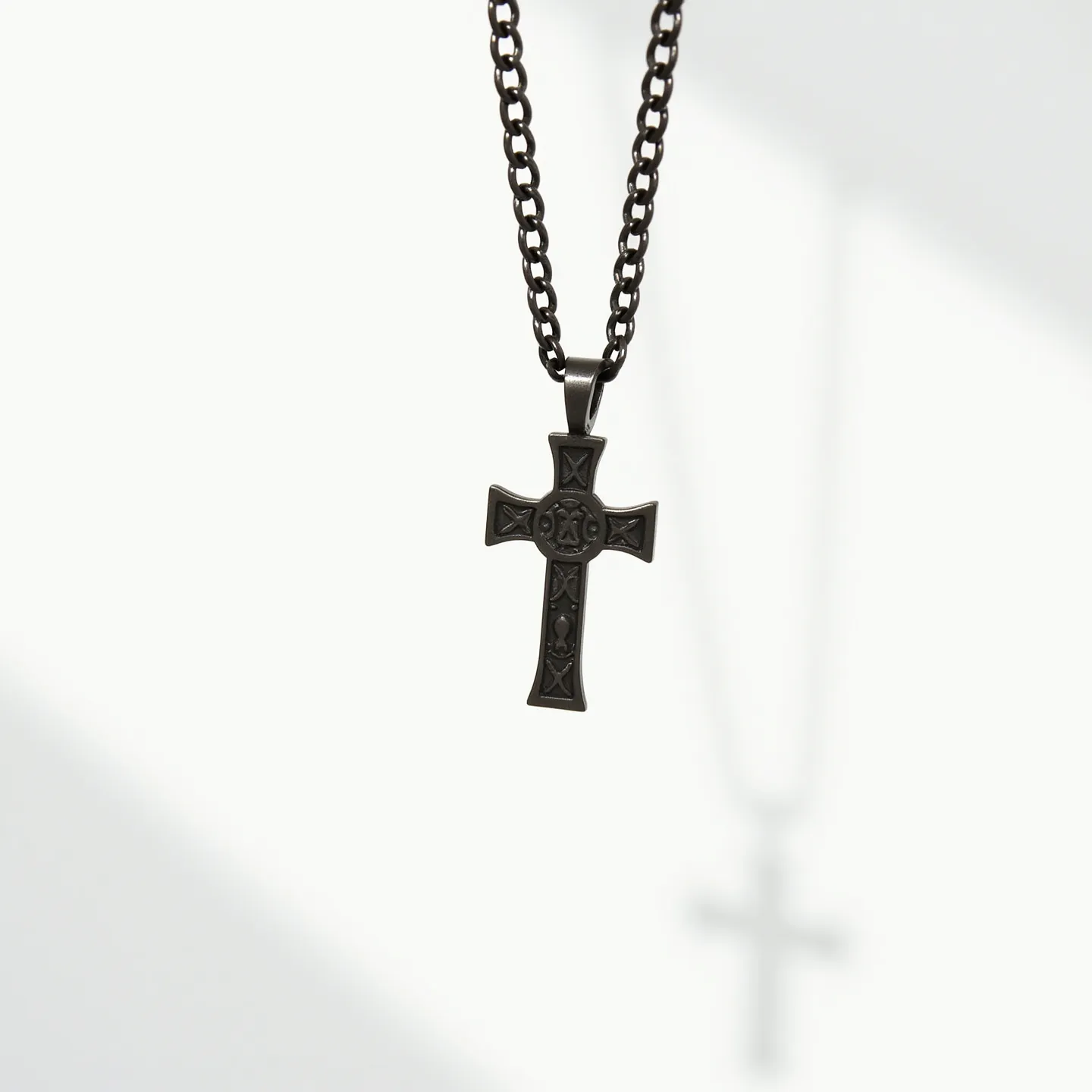 This boy's chain necklace features a sturdy, dark metal chain with interlocking links, providing a robust and masculine appearance. The centerpiece is a cross pendant, also crafted from a similar dark metal, with intricate detailing etched into the surface, showcasing ornate patterns. The pendant's design includes subtle embellishments, yet it lacks any gems or stones. The attachment of the pendant to the chain is seamless, suggesting a fixed bail connecting the two. The clasp is not visible, but the style is consistent with a typical chain necklace, indicating a functional and secure mechanism for wearing.