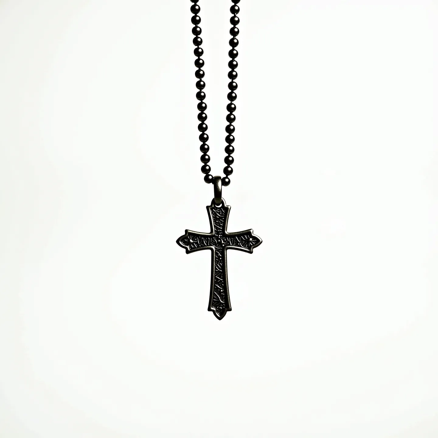 This boy's cross necklace features a sleek black design, with the cross pendant showing intricate patterns, giving it a textured appearance. The material appears to be a dark, possibly metal alloy, providing a modern and stylish look. The cross hangs from a simple ball chain, which complements the pendant's design. There are no visible gems or stones embedded in the cross, maintaining a minimalist aesthetic. The attachment seems secure and consistent with the overall dark theme of the necklace.