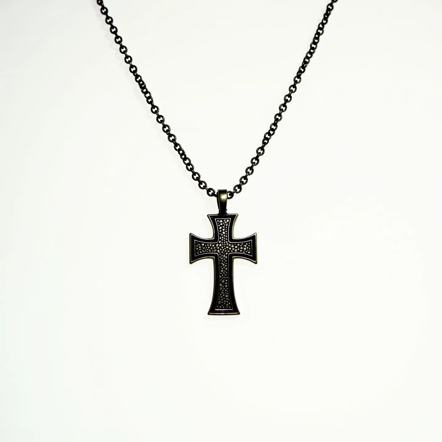 This boy's cross necklace features a sturdy, dark-toned metal chain that supports a distinctive cross pendant. The cross itself is richly adorned with a pattern of small, dark stones that create a textured look. These stones are uniformly set within the surface of the cross, contributing to its bold and modern design. The cross is suspended from a loop at the top, which seamlessly integrates with the chain, likely through a secure, simple attachment mechanism. The overall design combines elegance with contemporary style, making it suitable for both casual and formal wear.