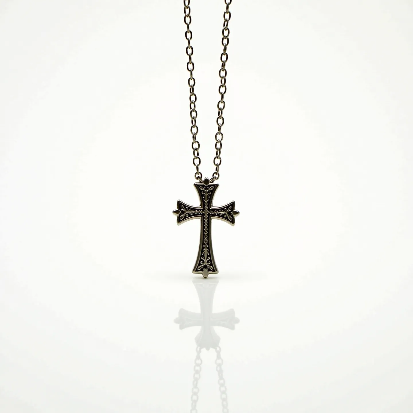 This boys cross necklace features a cross pendant crafted from a dark metallic material, possibly stainless steel or oxidized silver, giving it a sturdy and masculine appearance. The surface of the cross is adorned with intricate engraved patterns, adding a touch of elegance to its rugged design. The chain is composed of linked oval loops, matching the metallic tone of the pendant, and is likely made from a similar material for a cohesive look. The necklace appears to secure with a standard clasp mechanism, ensuring ease of wear and removal. Overall, the necklace combines durability with style, making it a suitable accessory for both casual and formal occasions.