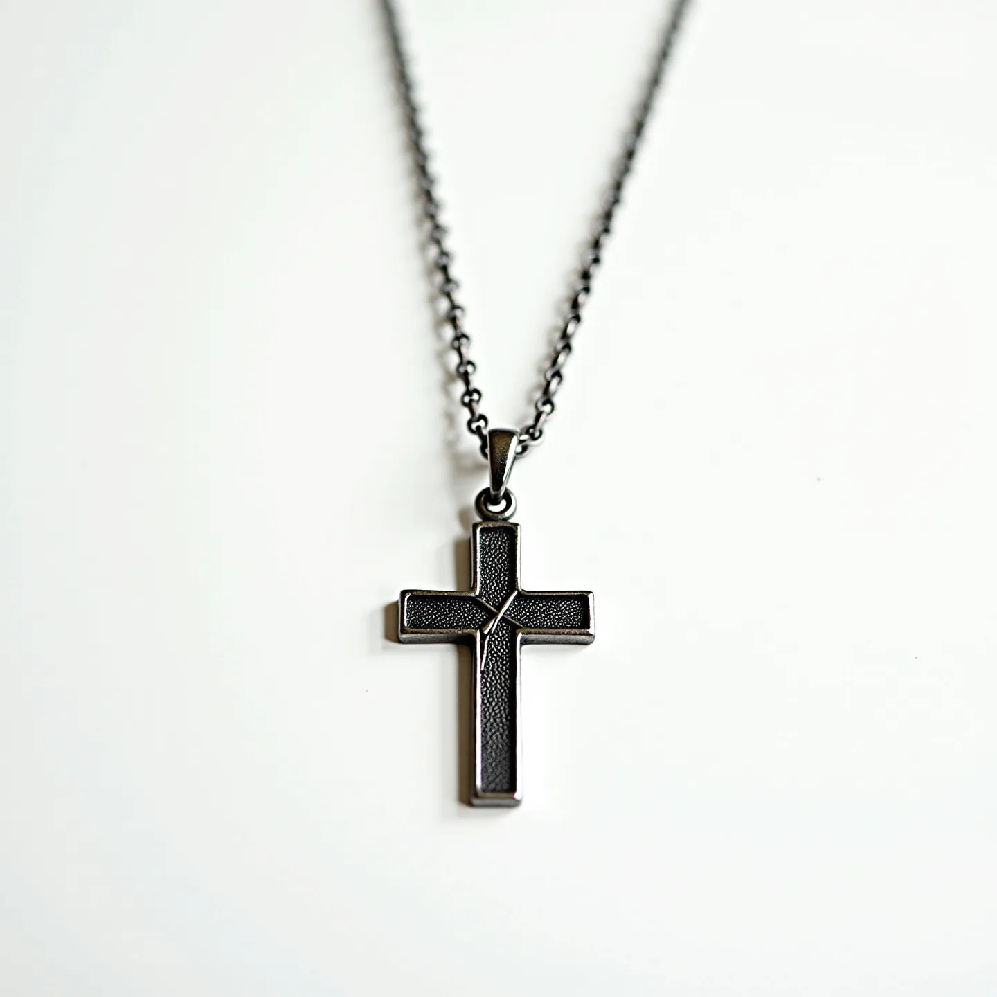 This boy's cross necklace features a sleek, metallic cross pendant with a textured design that suggests it's crafted from stainless steel or a similarly durable material. The cross is designed without any gemstones, emphasizing a minimalist and contemporary aesthetic. It is attached to a chain with small, evenly spaced links that complement the pendant's modern look. The necklace includes a standard clasp that ensures secure and easy wear, making it both a practical and stylish accessory.