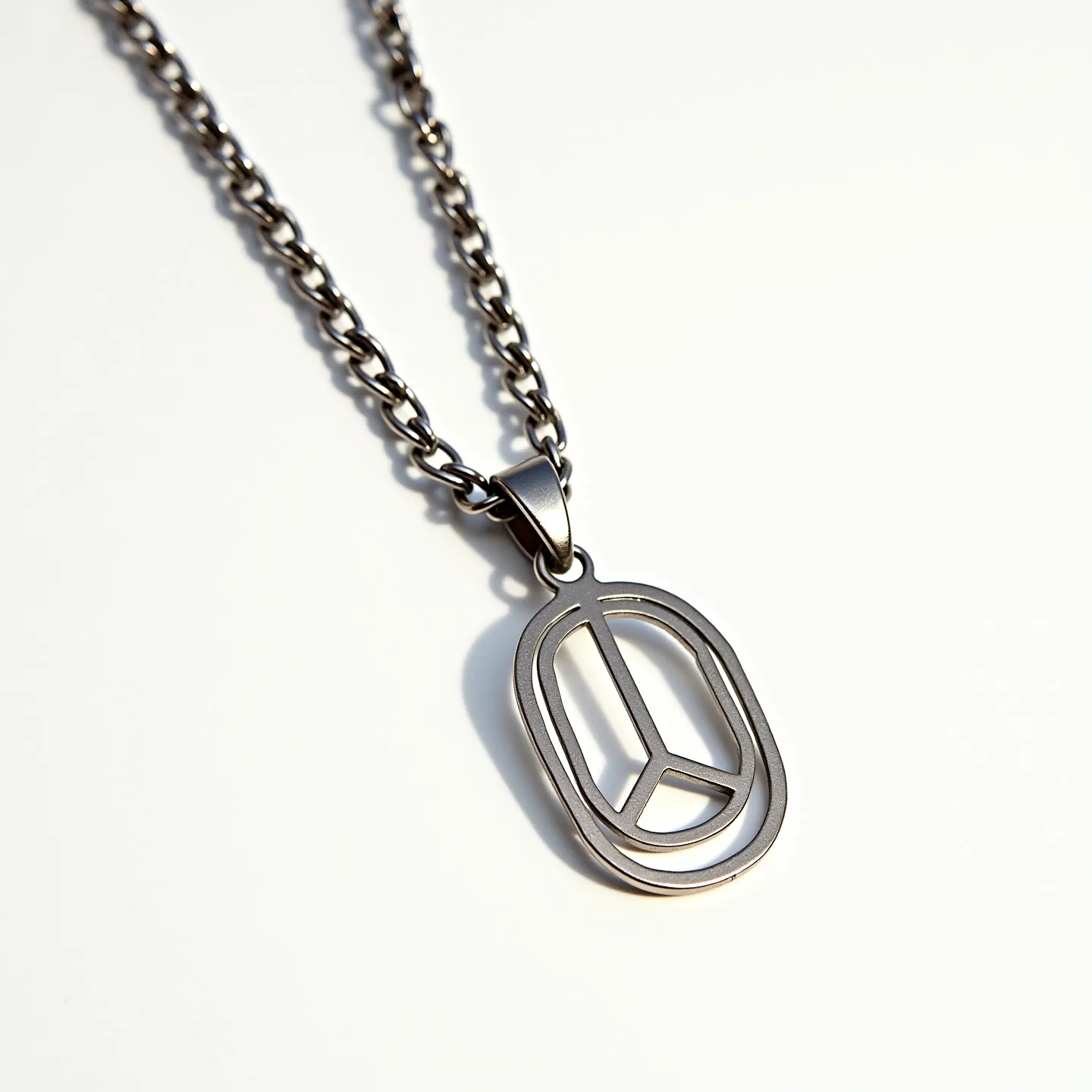 This boy's necklace features a robust chain made of a metallic material, likely stainless steel, given its smooth and shiny appearance. The pendant is designed in the shape of a peace symbol with an oval outline, matching the chain's material for a cohesive look. The necklace does not appear to showcase any gems or stones, focusing instead on the sleek, contemporary design of the metalwork. The pendant is attached to the chain with a simple bail, allowing it to hang freely. The chain likely uses a standard clasp, such as a lobster clasp, to secure it around the neck.