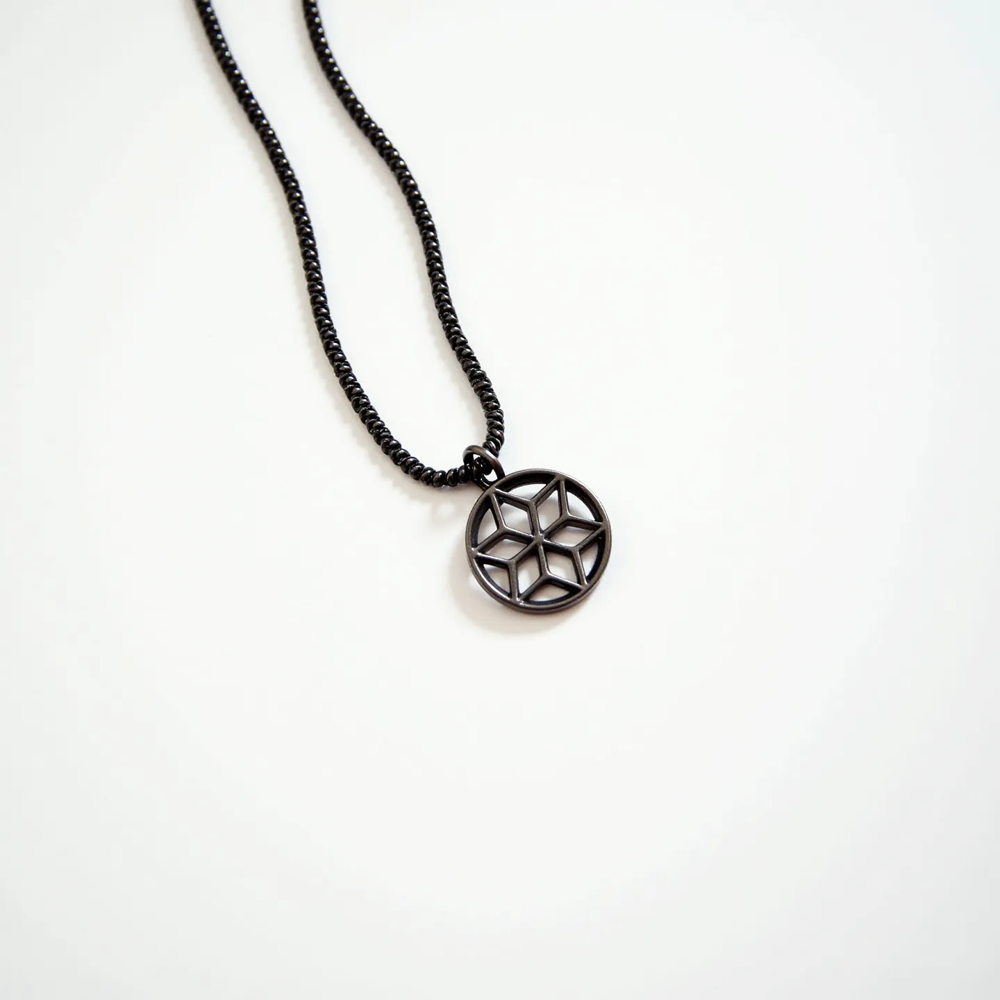 This boy's necklace features a black, metallic chain that is both sleek and understated. The pendant is a black, geometric star design, likely composed of a durable metal to maintain its intricate pattern, framed by a circular boundary. The absence of gems or stones suggests a minimalist aesthetic focused on metallic elements. The chain and pendant are connected by a small loop, and the necklace likely has a simple clasp mechanism, though the clasp is not visible. Overall, the necklace combines modern design with a focus on geometric symmetry.