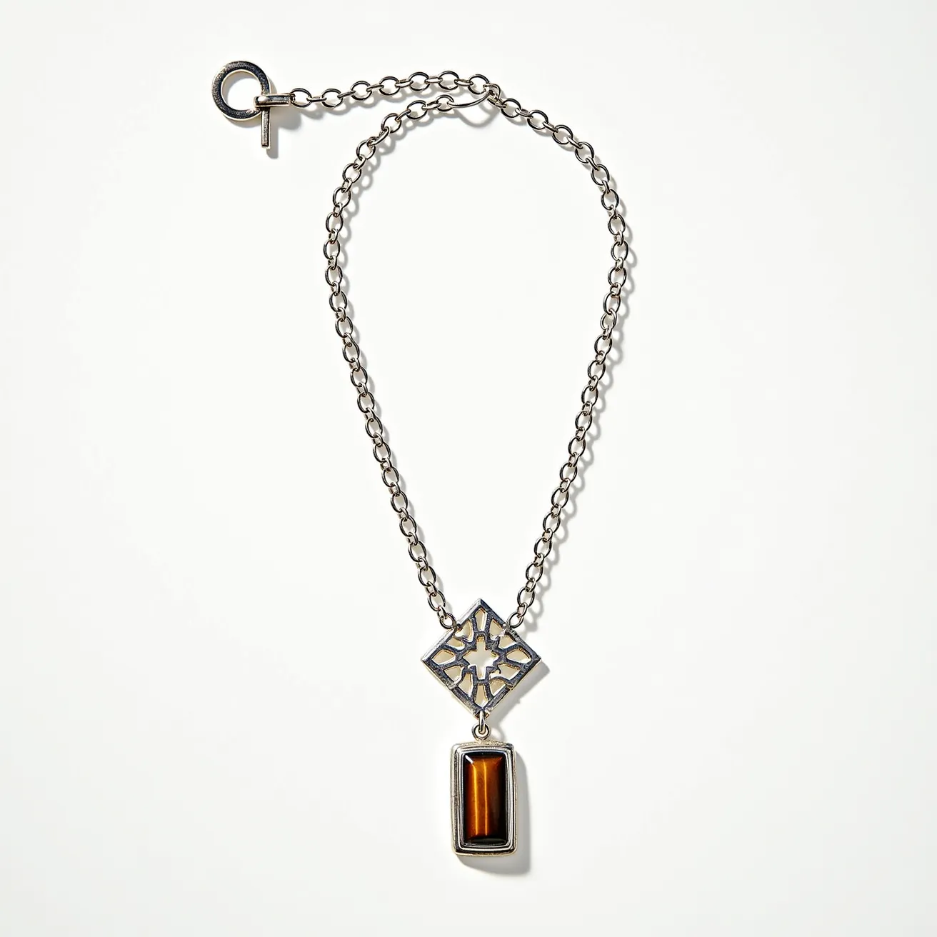 This boy's necklace features a chain made of metal links, suggesting durability and a sleek appearance. The centerpiece is a geometrically designed pendant with an intricate cut-out pattern, adding an artistic element to the necklace. Dangling below is a rectangular setting housing a polished, cabochon-cut brown gemstone, likely resembling tiger's eye, which is known for its silky luster and rich color. The necklace is secured with a toggle clasp, providing a classic and secure method of attachment while enhancing the necklace's overall aesthetic appeal.