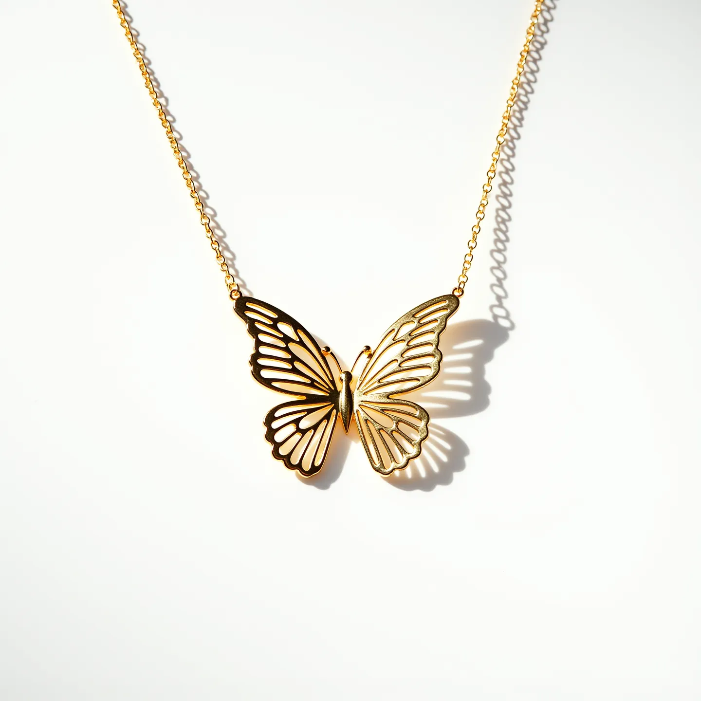 This butterfly necklace features a delicate and intricately designed butterfly pendant crafted from metal with a gleaming gold finish. The pendant showcases an openwork style that highlights the elegant wing patterns of the butterfly. The necklace is secured with a fine chain that complements the pendant's airy design. It is equipped with a standard spring ring clasp, ensuring a secure and adjustable fit. The overall effect is a graceful and charming piece of jewelry that captures the beauty of a butterfly in mid-flight.