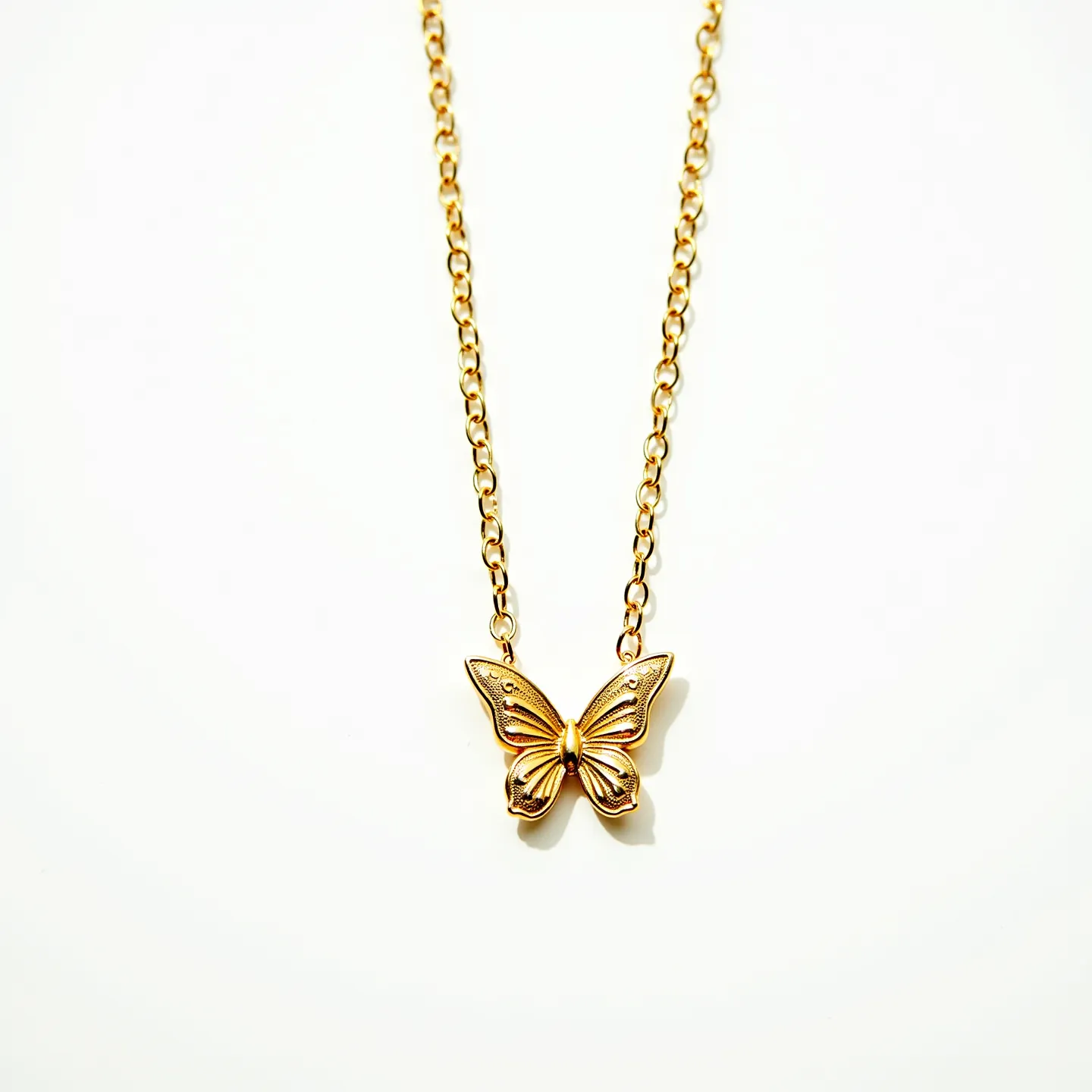 This butterfly necklace features an elegant gold-toned chain that supports a detailed butterfly pendant. The pendant is crafted with delicate engravings on its wings, adding texture and allure. It appears to be made of metal, likely gold-plated, as indicated by its luster and hue. The necklace includes a simple chain with evenly spaced links, suggesting a secure and easy-to-use clasp at the back. The absence of visible gems or stones keeps the focus on the intricate design of the butterfly, making it a versatile and stylish accessory.