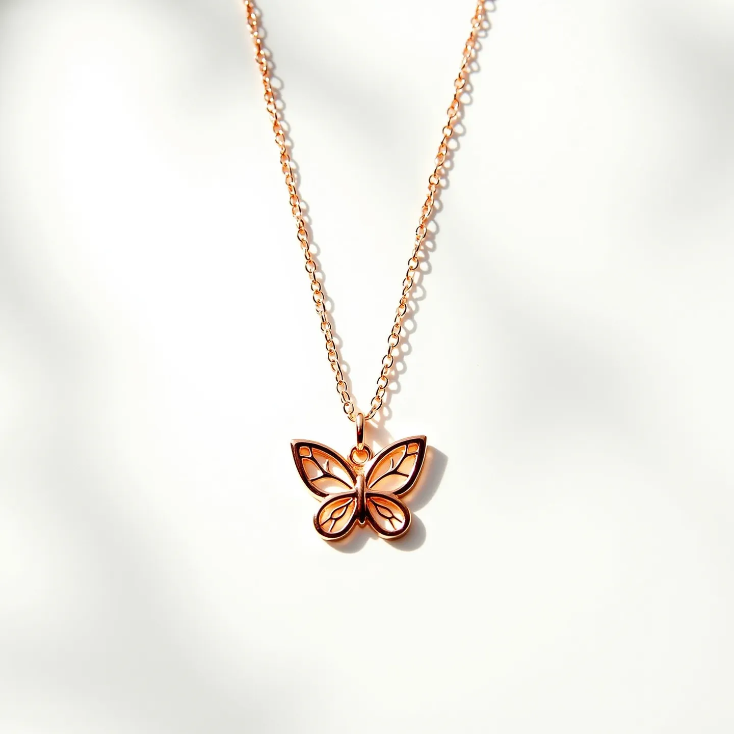 This butterfly necklace features a delicate chain that appears to be crafted from rose gold. The pendant is an intricately designed butterfly, showcasing cut-out sections that create a graceful and airy appearance. The smooth lines and polished finish highlight the elegance of the piece. There do not appear to be any stones or gems, keeping the design simple yet sophisticated. The necklace is likely secured with a typical clasp suitable for necklaces, ensuring ease of wear and security.