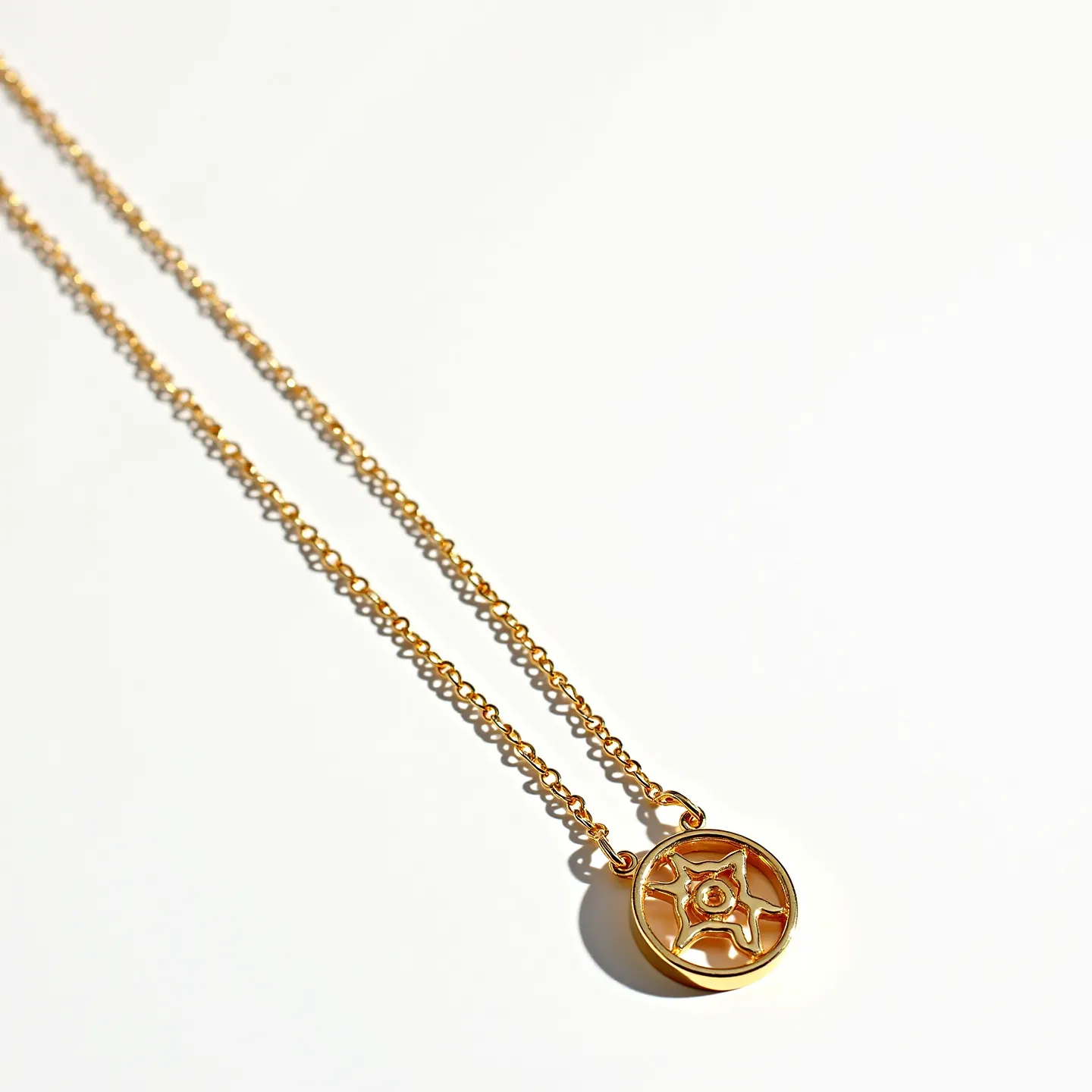 This cable chain features interlocking links crafted from a metal with a gold finish, providing a classic and elegant appearance. Attached to the chain is a circular pendant with an intricate five-point star design in the center. The star encases a small, round gemstone positioned in the middle, which adds a subtle touch of sparkle to the piece. The pendant appears to be secured within a bezel setting, ensuring stability and a sleek outline. The design and materials suggest a blend of simplicity with a hint of sophistication, making it suitable for various occasions.