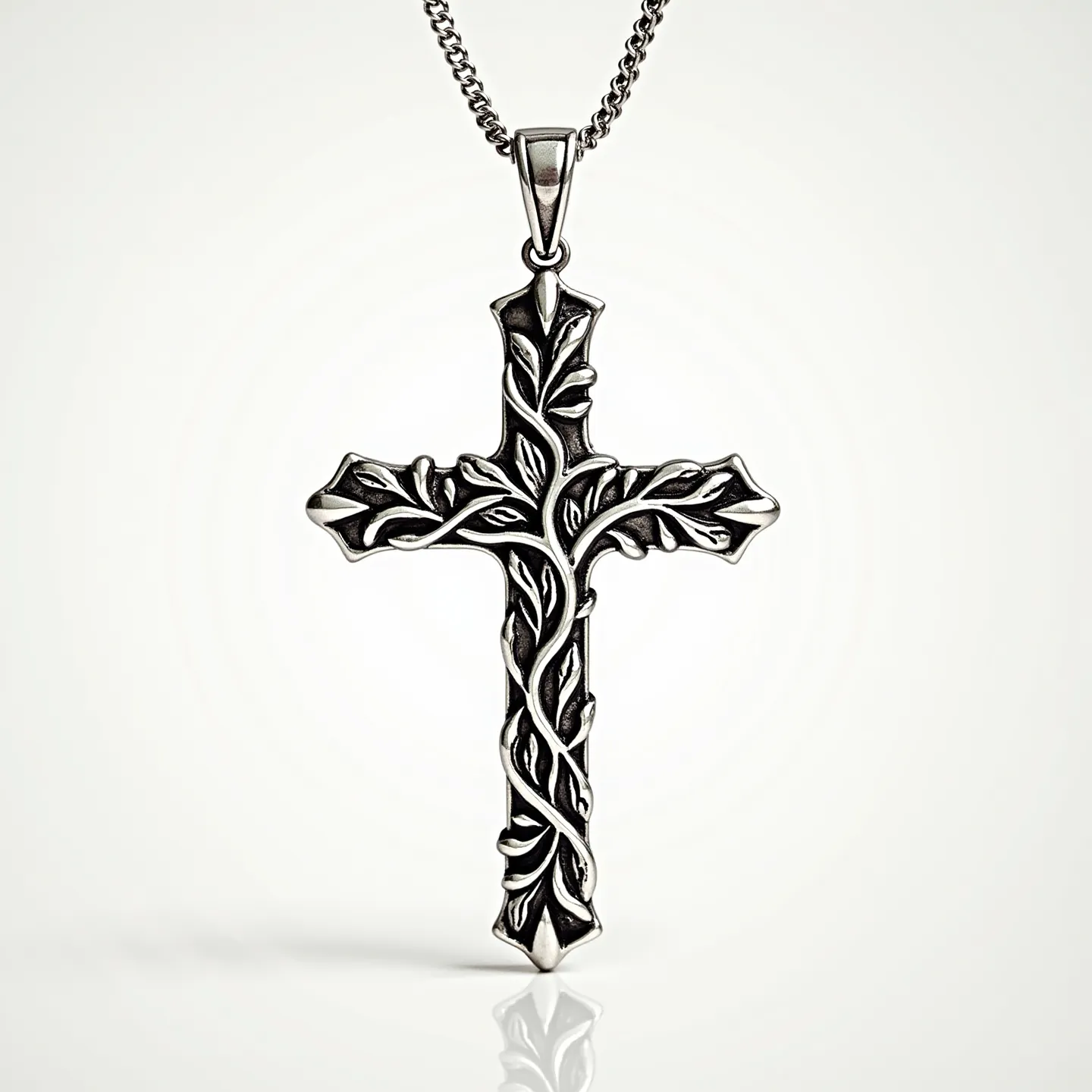 This Catholic cross necklace features an intricately designed cross made from a silver-toned metal, showcasing detailed vine and leaf motifs that give it a refined, ornamental appearance. The elegant vines wrap harmoniously around the vertical and horizontal arms of the cross, creating a sense of movement and life. Attached to a delicate chain with a standard loop at the top, the cross is both secure and easy to wear. The chain appears finely crafted, complementing the artistic design of the cross.