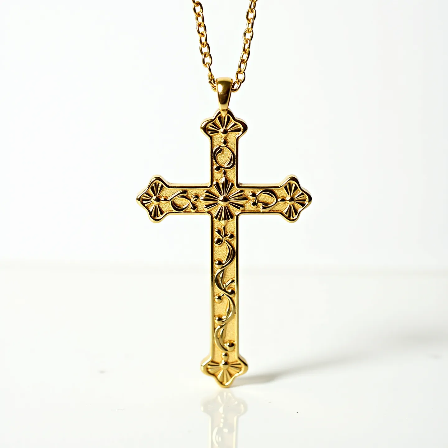 This catholic cross necklace showcases an intricately designed cross pendant, crafted from what appears to be a gold-tone metal, emphasizing a classic and elegant aesthetic. The pendant features a series of embossed ornamental patterns, including floral motifs and circular designs, lending it an ornate and decorative appeal. The cross hangs from a delicate chain that complements the pendant's refined style. A standard lobster clasp at the end of the chain provides a secure and functional closure, ensuring the necklace remains comfortably in place when worn. The artisanal details in its design reflect traditional craftsmanship.