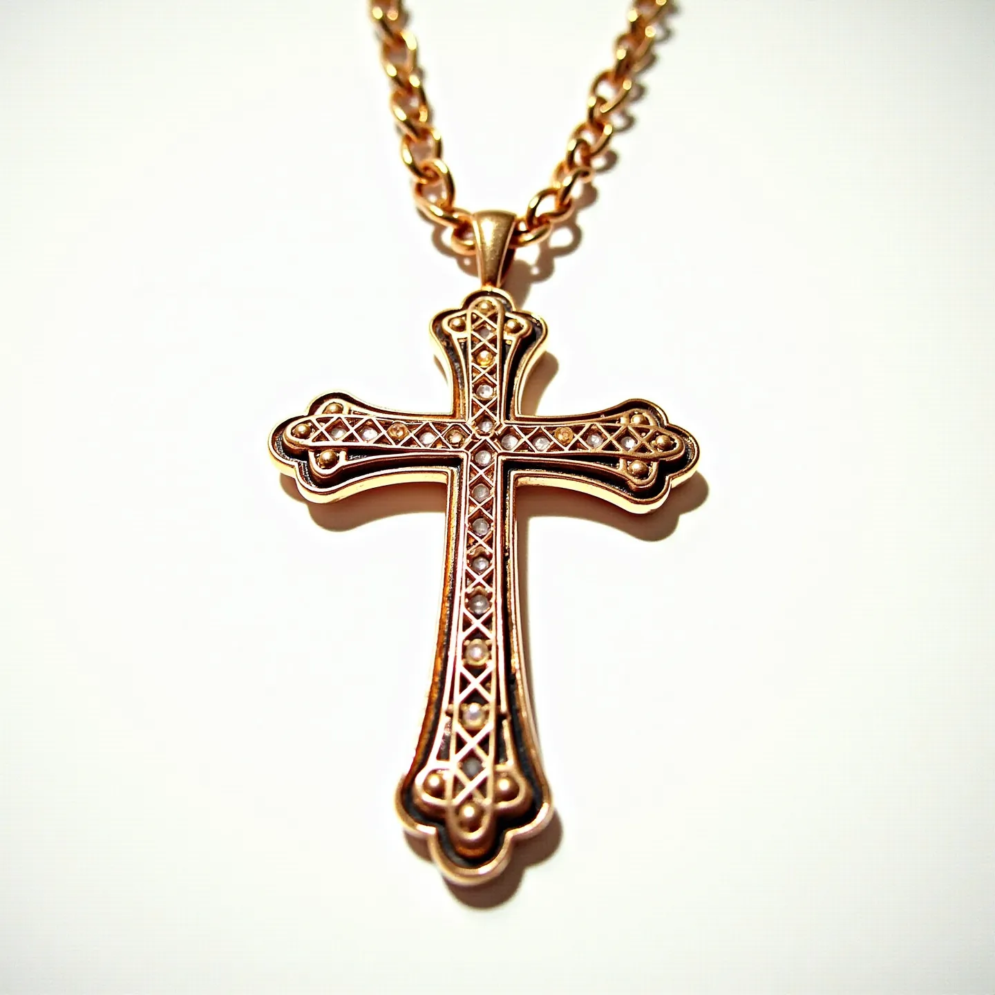 This catholic cross necklace features an intricate design with a gold tone, highlighting a detailed filigree pattern throughout the cross. The cross is adorned with a series of small, round, clear stones set in a symmetrical pattern, possibly resembling diamonds or another clear gemstone. These stones are set in a prong setting, adding elegance and sparkle to the design. The cross is attached to a medium-thick chain with closely linked, oval-shaped links, which provides durability and complements the ornate cross. The necklace is secured with a simple, classic lobster clasp, ensuring a secure fit while worn.