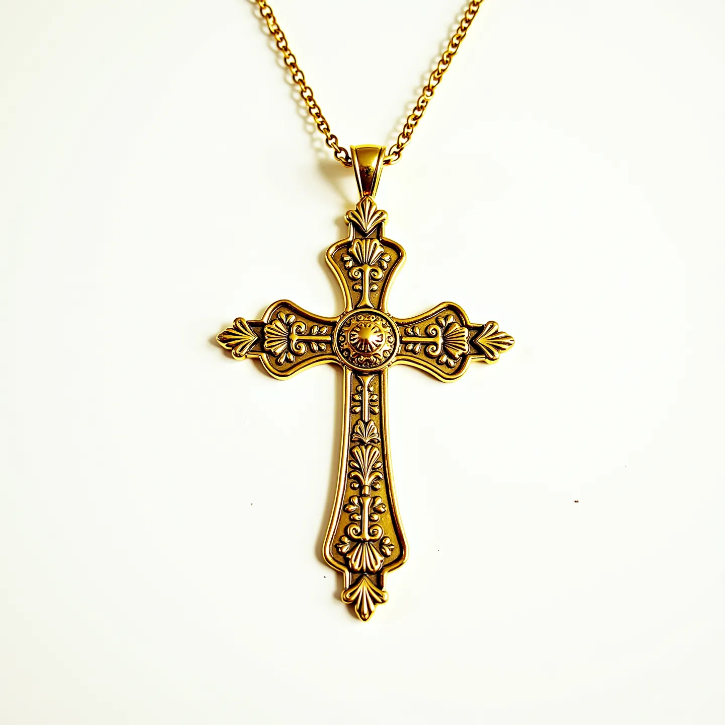 This catholic cross necklace features a detailed and ornate design, likely crafted from metal with a gold-tone finish. The cross showcases intricate floral and foliage patterns, adding elegance and a touch of antiquity. At the center of the cross is a circular ornamental feature that resembles an engraved emblem or embellishment, enhancing the visual appeal. The chain is composed of interlinked metal loops that suggest a sturdy construction, secured by a standard connecting mechanism, possibly a lobster clasp or similar attachment. The overall design exudes a classic and timeless charm, making it a meaningful accessory.