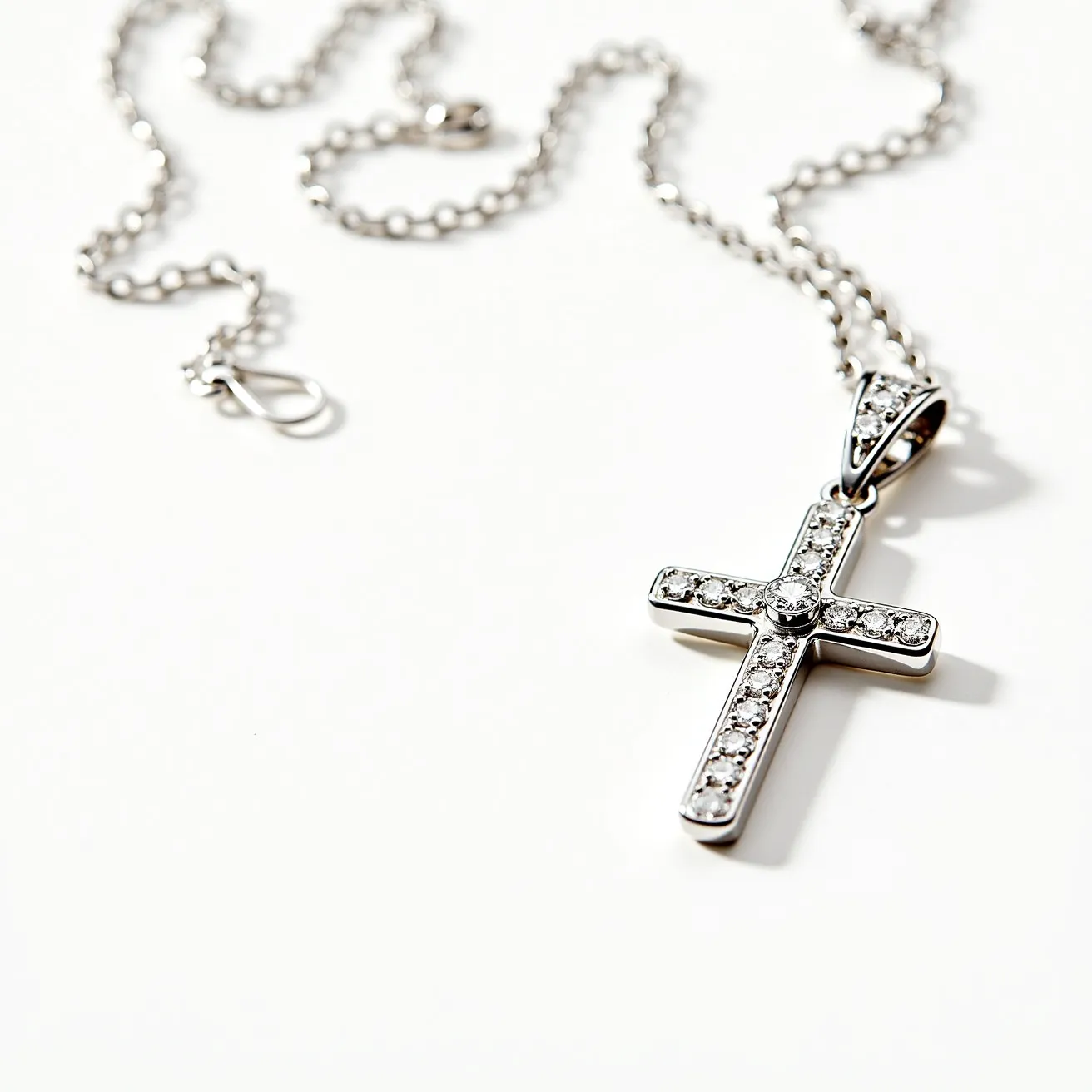 This Catholic necklace features a delicate chain made of what appears to be a shiny metal, likely silver or white gold, complementing its elegant design. At its center is a cross pendant adorned with small, round-cut gems, possibly diamonds or cubic zirconia, set into the surface in a pave style that ensures a continuous sparkle. The cross has a simple yet striking bail that connects it seamlessly to the chain. The chain itself is equipped with a secure lobster clasp, allowing for easy wear and removal while maintaining a stylish and secure attachment to the pendant.