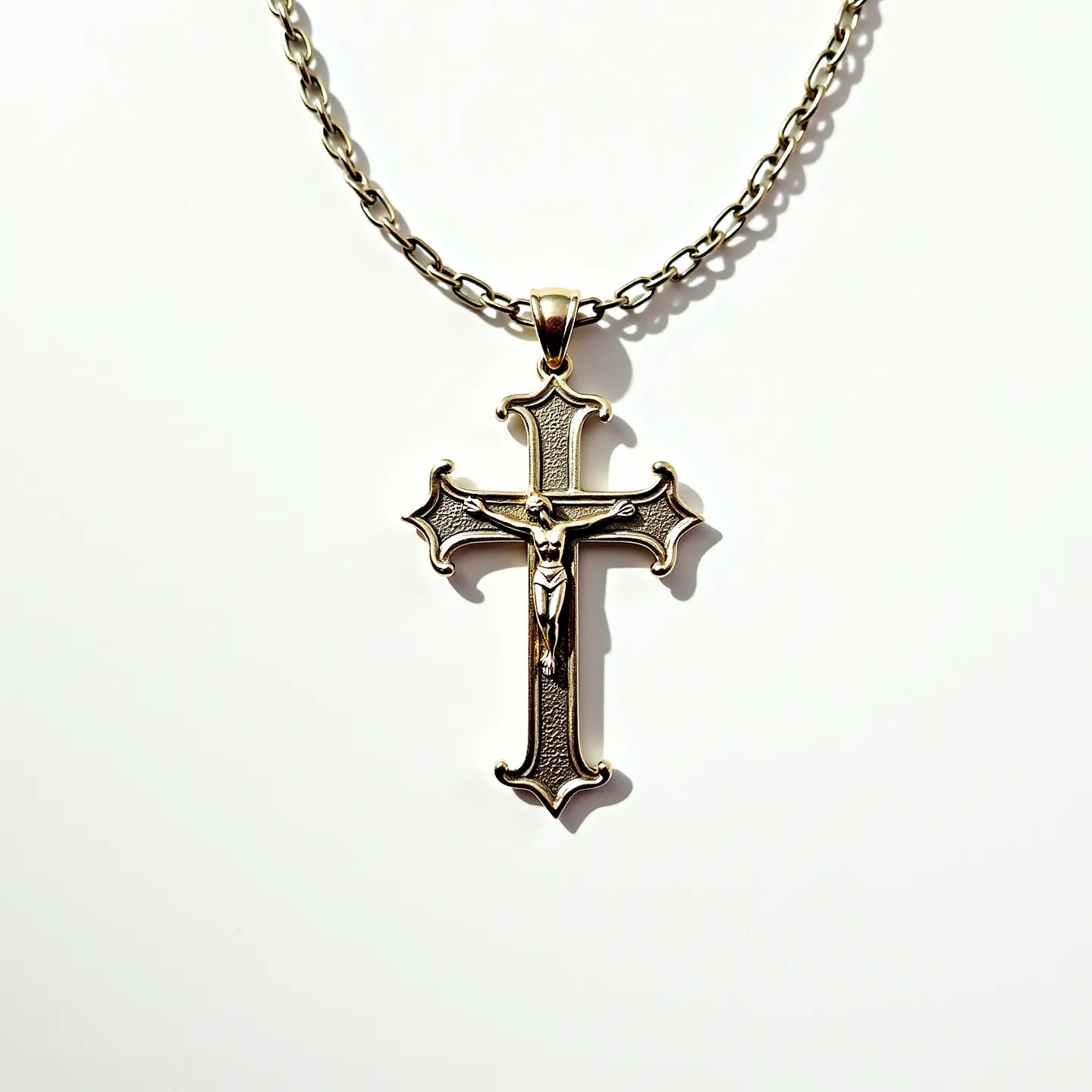 This catholic necklace features a prominent crucifix pendant crafted from a polished metal, likely gold or gold-plated, which showcases intricate detailing of the figure of Christ on the cross. The cross itself possesses an ornate design, with flared ends and textured surfaces that add depth and elegance. The necklace is completed with a sturdy metal chain, consisting of tightly linked oval loops, providing durability and a classic appearance. A simple bail connects the pendant to the chain, ensuring the crucifix hangs securely. The absence of gemstones or elaborate settings highlights the understated beauty and spiritual significance of the piece.