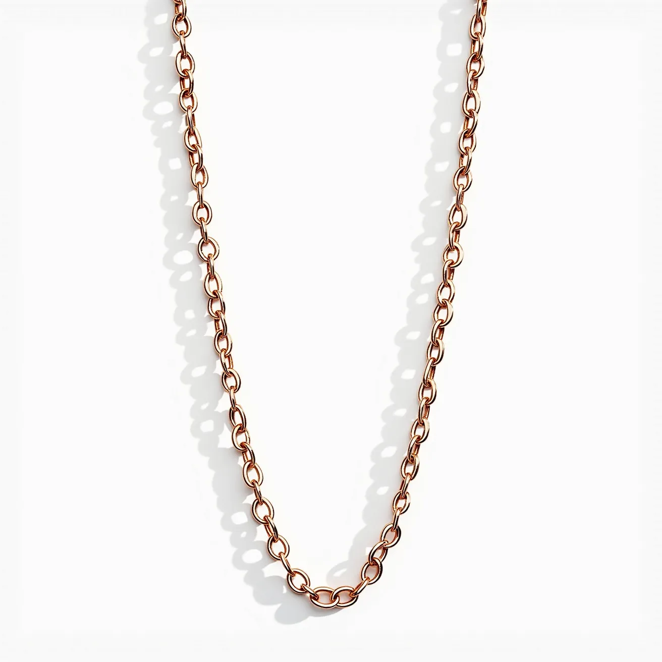 This chain link necklace is crafted from a material that appears to have a warm, rose-toned finish, suggesting it may be made of rose gold or copper. The necklace features interconnected oval links, giving it a classic and versatile design. There are no visible gems or stones set within the necklace, emphasizing the simplicity and elegance of the metal links. The necklace also includes a small lobster claw clasp, which is functional and secure for attachment.