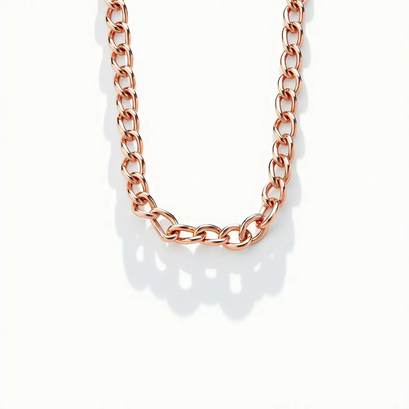 This chain link necklace features interconnected oval links with a polished rose gold appearance, giving it a warm, metallic shine. The consistent size and shape of the links suggest uniformity and elegance, indicative of a classic style. There are no visible gems or stones adorning the necklace, allowing the focus to remain on the sleek, reflective quality of the metal itself. The absence of a visible clasp in this view suggests it may be integrated seamlessly within the design or located outside the visible section of the necklace. The overall aesthetic reflects a minimalist yet sophisticated design, suitable for both casual and formal wear.