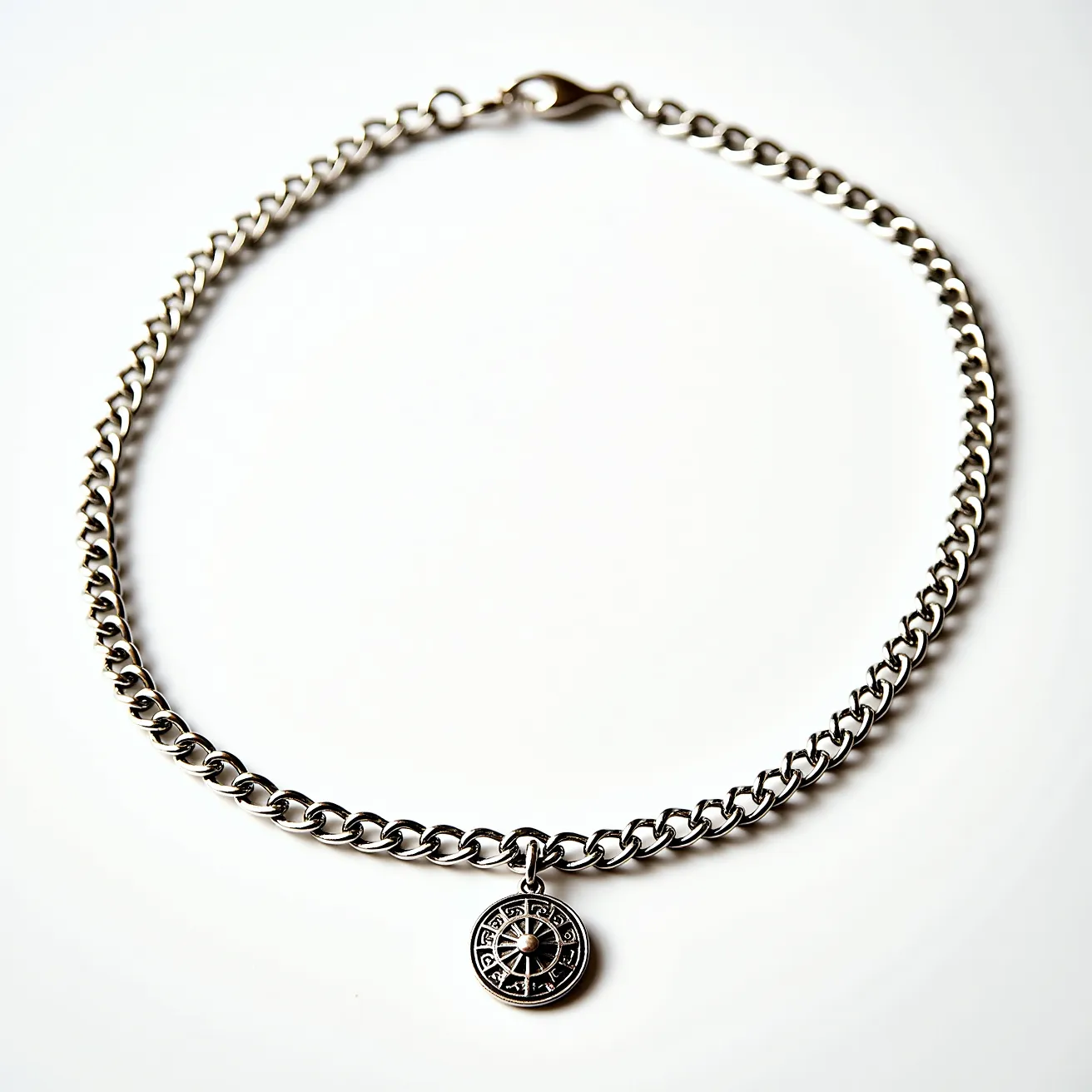 This chain link necklace features a series of interlocking metallic links, likely made from silver or stainless steel, giving it a sleek and polished appearance. The necklace is adorned with a circular pendant that appears to have intricate details or engravings, possibly inspired by geometric or symbolic patterns. At its center, there is a small mounted stone or bead adding a touch of elegance. The necklace secures with a lobster clasp, ensuring a sturdy and reliable closure for everyday wear.