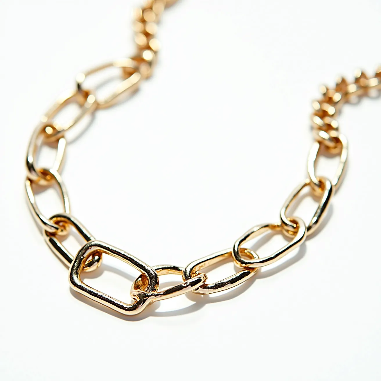 This chain link necklace is composed of elongated oval links crafted from a polished gold-toned metal, giving it a sleek and stylish appearance. The links vary in size, with some being longer and more rectangular, contributing to its contemporary design. There are no visible gemstones or ornamental settings, maintaining a minimalist aesthetic focused on the shine and luster of the metal itself. A clasp is not visible in the image, implying it may be integrated or of a discreet design, allowing the necklace to elegantly encircle the neck.