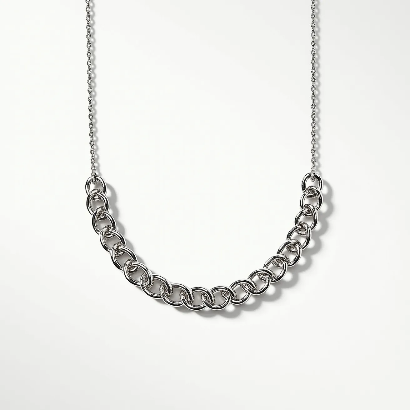 This chain link necklace features elegantly interlocking loops in a polished silver-colored metal, creating a bold statement piece. The links are likely made from stainless steel or a similar metallic material, providing durability and a sleek finish. The necklace does not include any gems, stones, or additional embellishments, purely showcasing the intricate design of the links themselves. It is connected by a delicate chain that adds contrast to the heavier chain links. The clasp is not visible in this image, suggesting it could be a discreet lobster or spring ring clasp commonly used in such designs for seamless wearability.