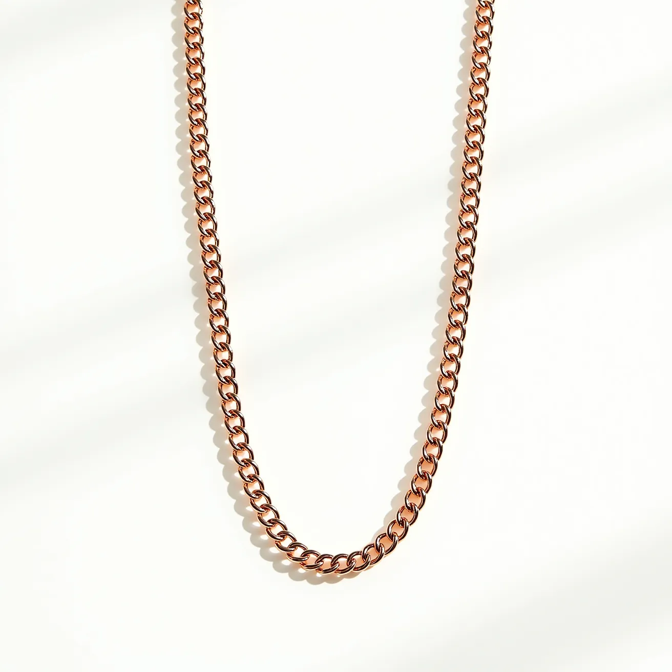 This chain link necklace features a series of interlocking, uniform links with a metallic finish, likely composed of polished metal with a rose gold tone. The design is sleek and classic, emphasizing the smooth curvature and shine of the links. It exhibits a timeless elegance without the inclusion of any gemstones or ornate settings. The clasp is likely a standard lobster or spring ring style, providing secure fastening and ease of wear.