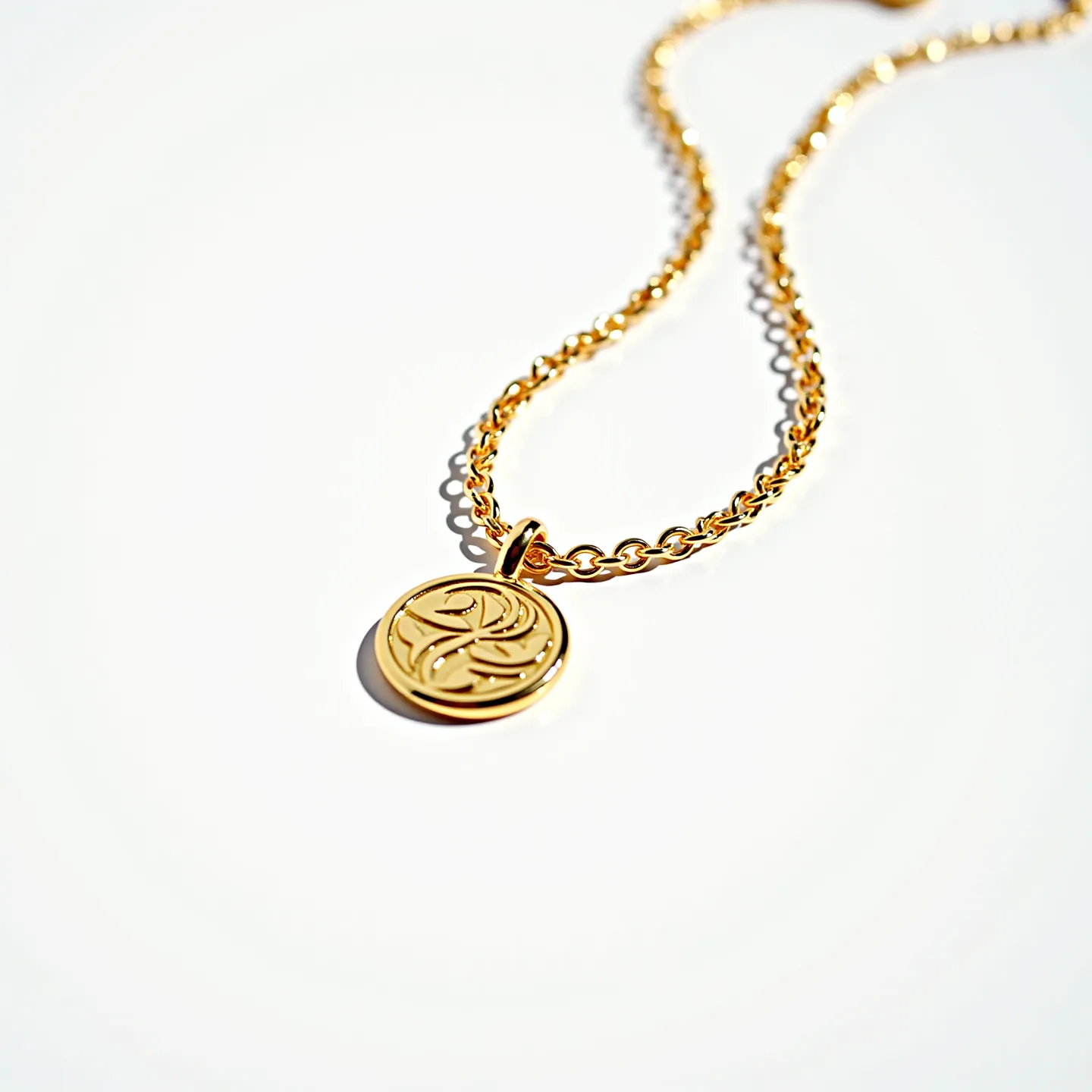 This charm necklace features a lustrous gold chain and is highlighted by a circular gold charm with intricate engraving. The chain links are polished, reflecting light elegantly, creating a sleek and sophisticated appearance. The charm is seamlessly attached to the chain with a polished bail, allowing it to hang freely. There are no gems or additional stones adorning the necklace, emphasizing its minimalist yet elegant design. The necklace is secured with a standard gold-colored clasp, ensuring durability and ease of wear.