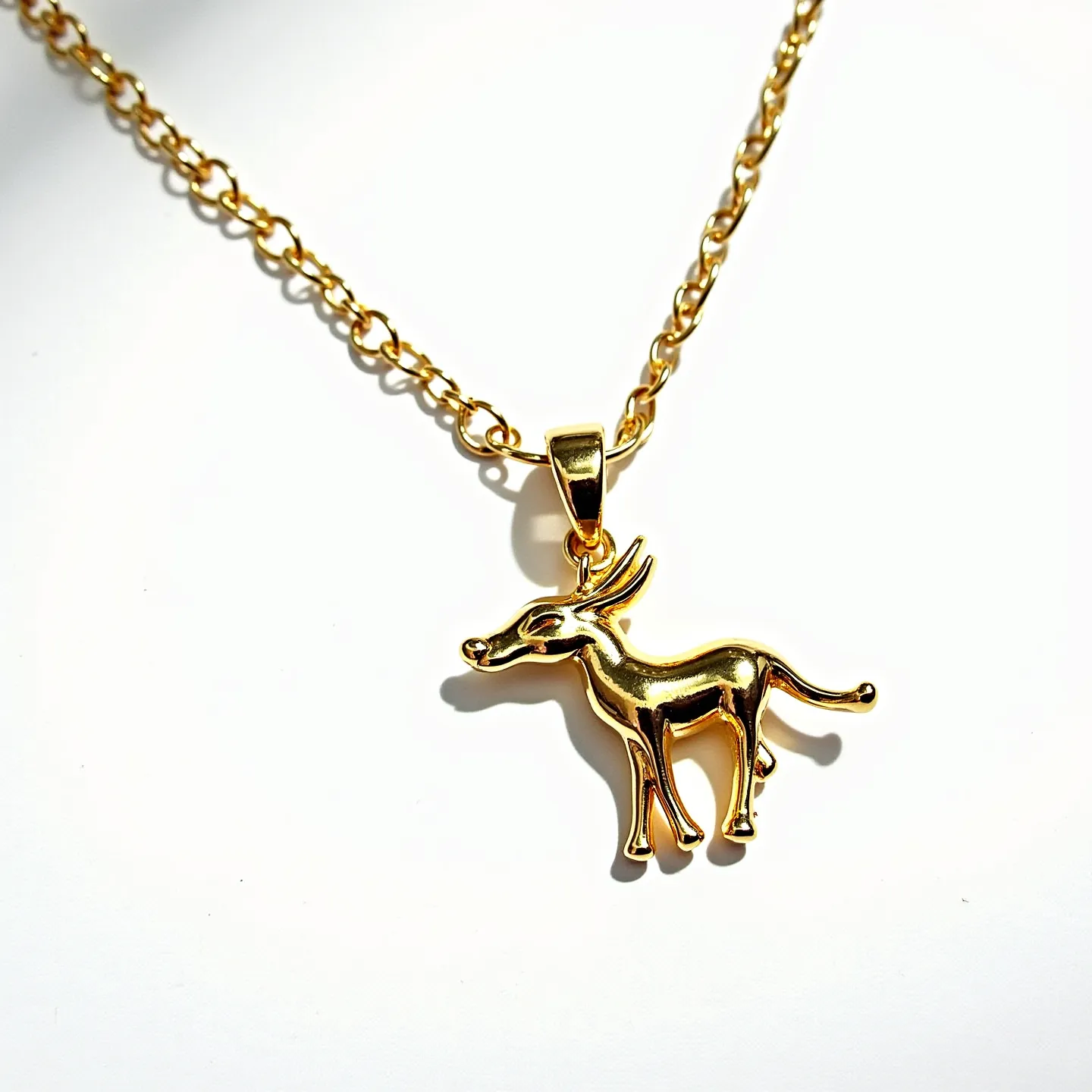 This charm necklace features a polished gold-toned chain, showcasing a pendant in the form of an antelope. The pendant captures a sleek, elongated form with distinct horn details, contributing to its elegant appeal. The necklace is designed with an elongated link chain, providing a classic and versatile look that complements the charm. The pendant is attached to the chain using a smooth, integrated bail, ensuring a secure and stylish connection. The overall design reflects a minimalist elegance, highlighting the animal motif as a central and eye-catching element.