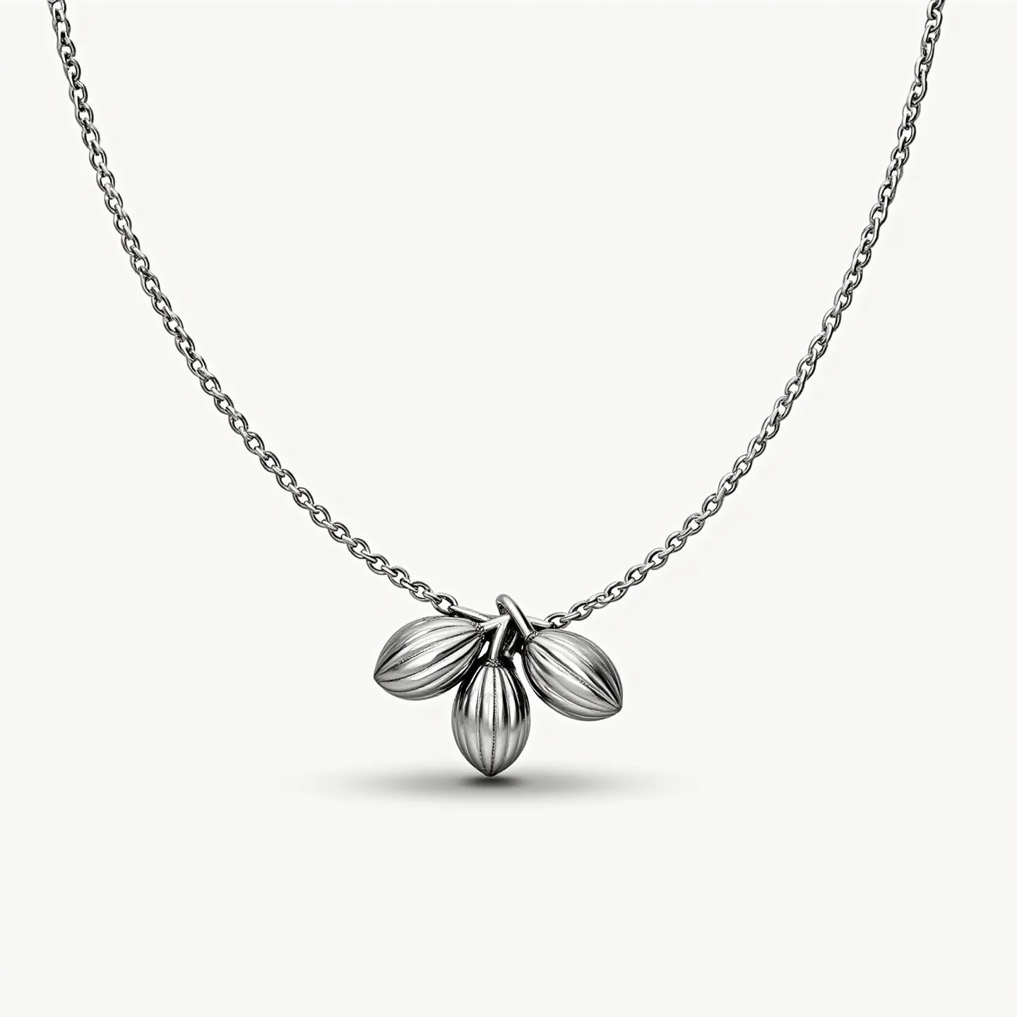 This charm necklace features a delicate link chain crafted from polished metal, possibly silver or white gold, lending it a refined and elegant appearance. The central attraction consists of three charms, artistically designed to resemble almond-shaped pods, each with distinct ridges that add texture and dimension. The charms are suspended from a central loop directly connected to the chain, creating a cohesive and integrated design. The chain is completed with a simple yet secure clasp, ensuring ease of wear while maintaining its stylish appeal.